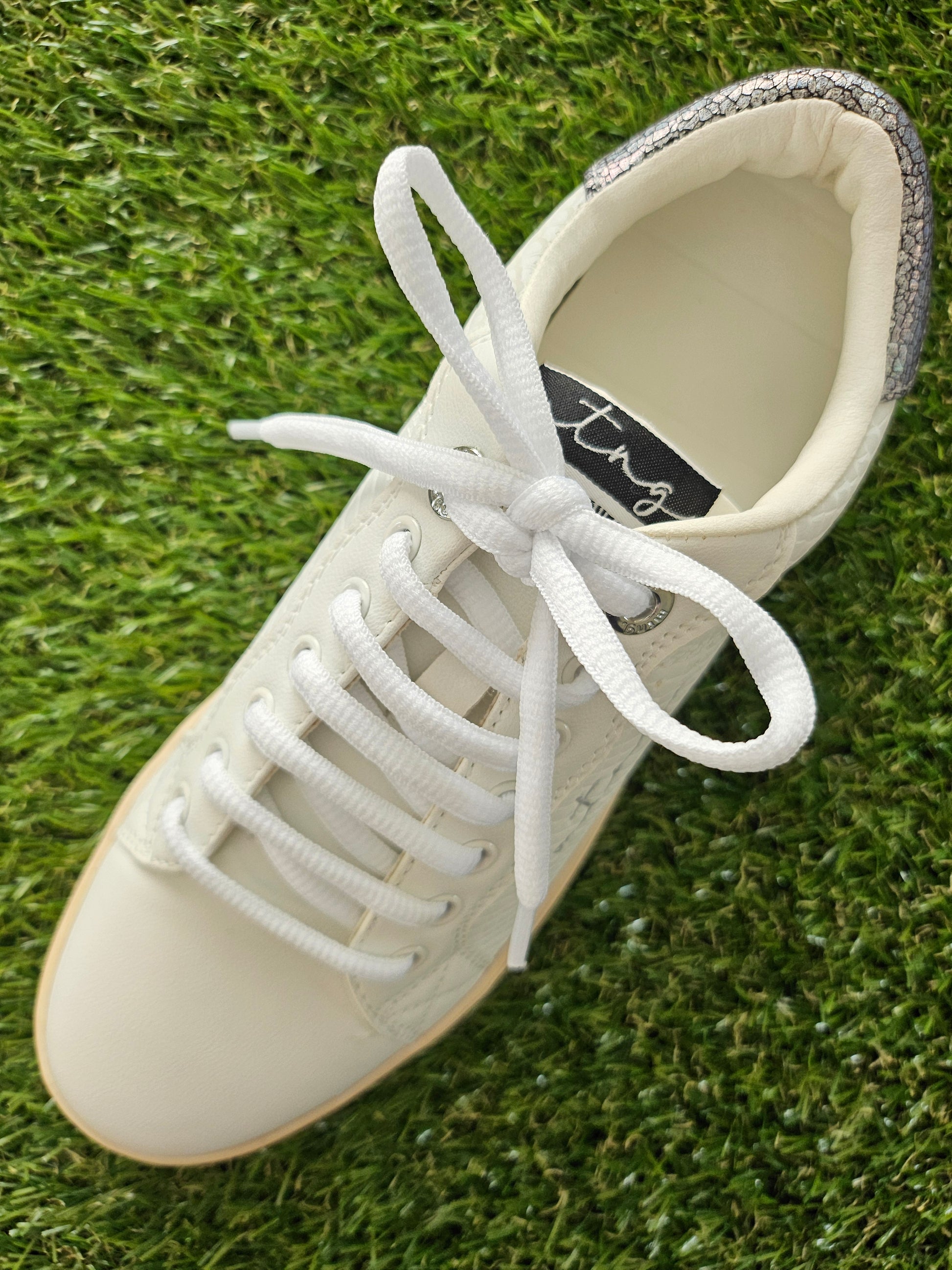 White sneaker with white laces on a grass background