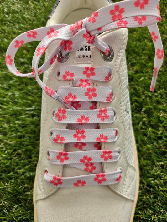 White shoe with floral-patterned laces on a grass background