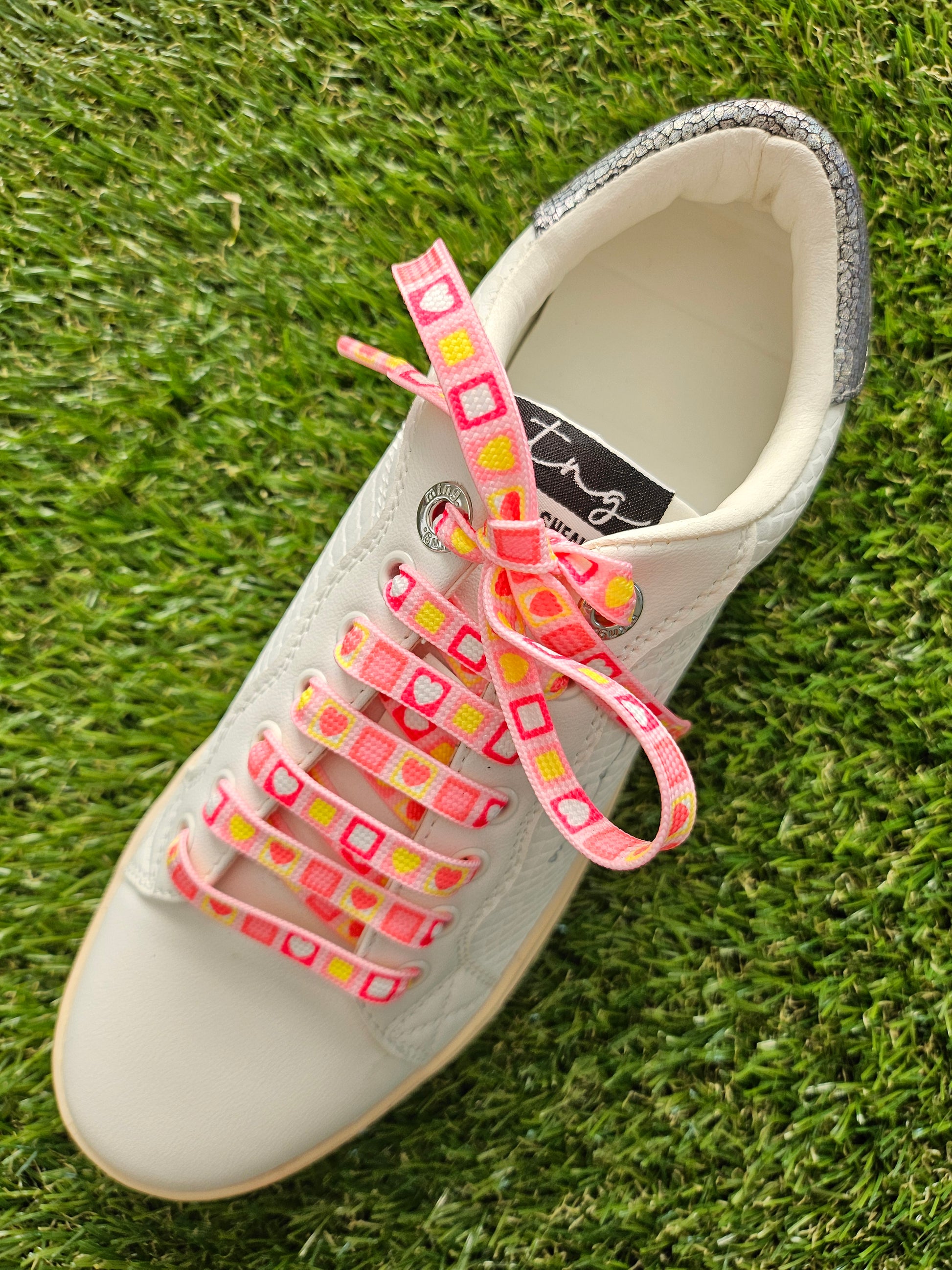 Pretty Pink Square ShoeLaces on green grass in a white trainer