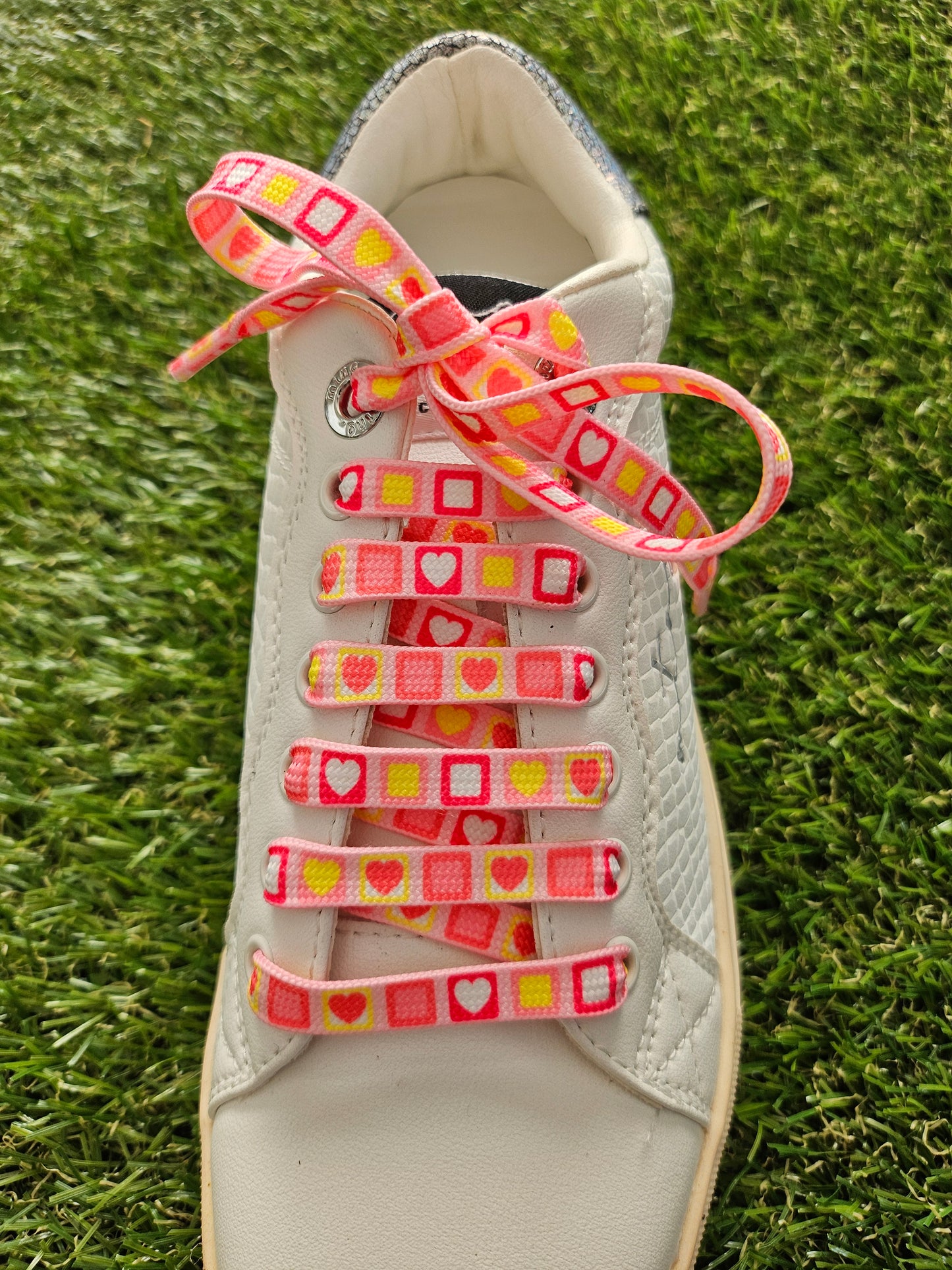 pink laces in a white shoe on grass