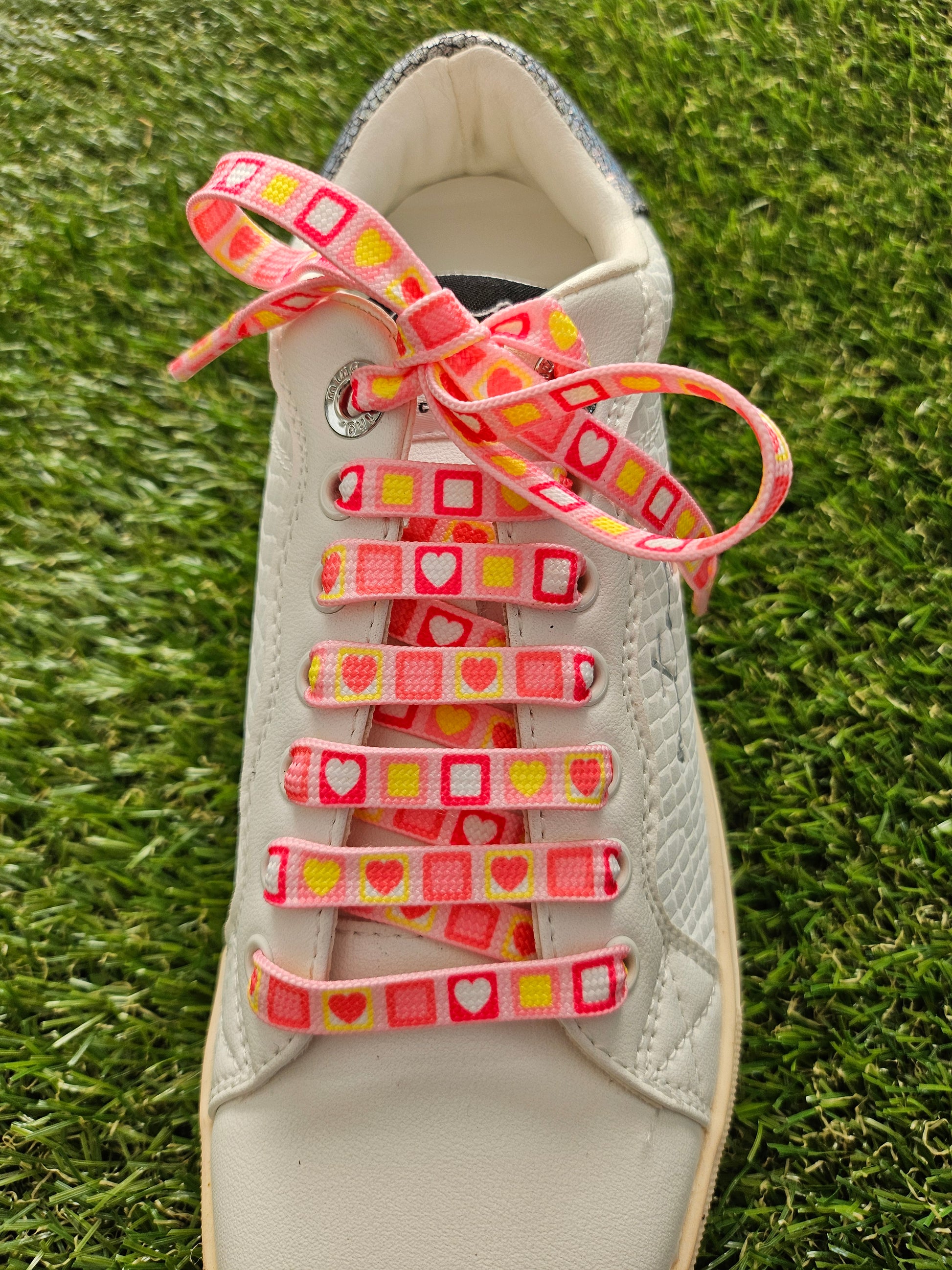 pink laces in a white shoe on grass