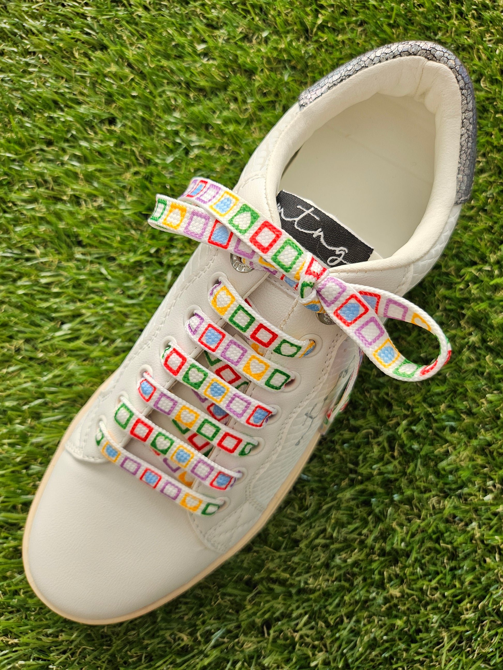 White sneaker with colorful laces on grass