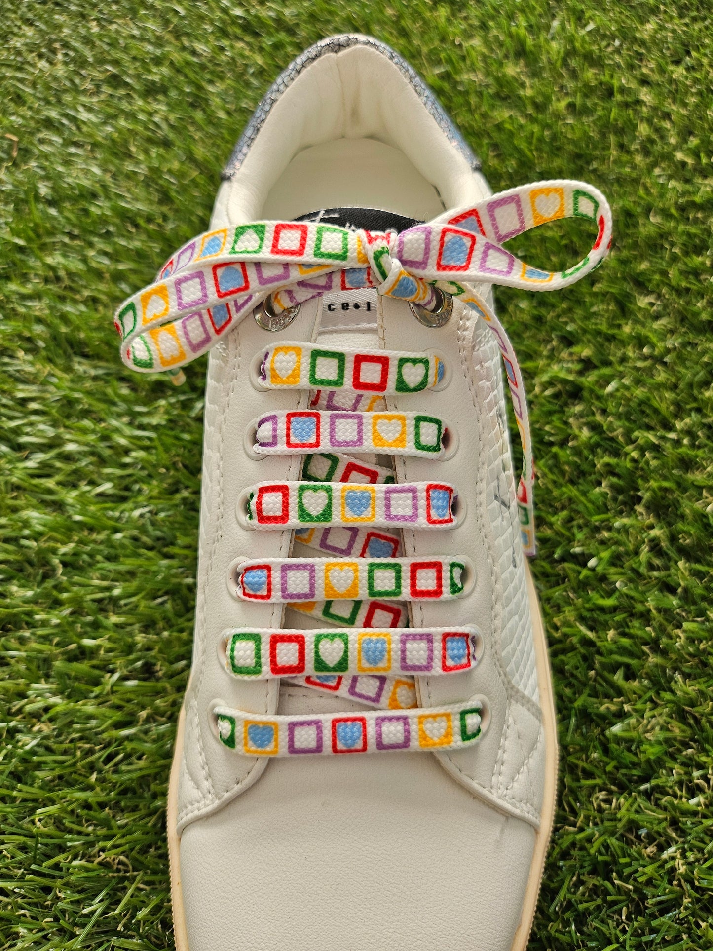 Colorful shoelaces on a white shoe on grass