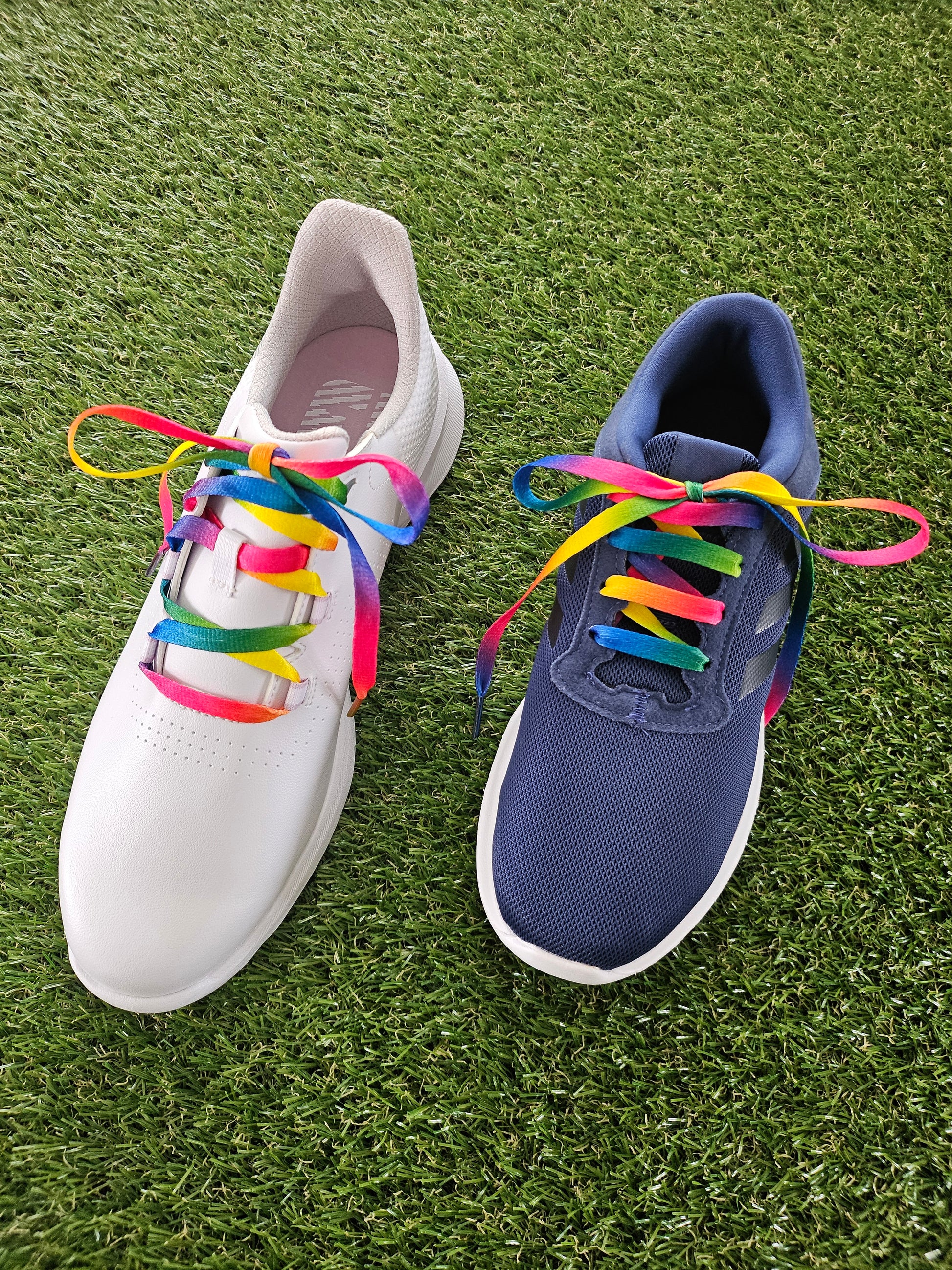 Blue and white trainers with colorful shoelaces on a grassy surface