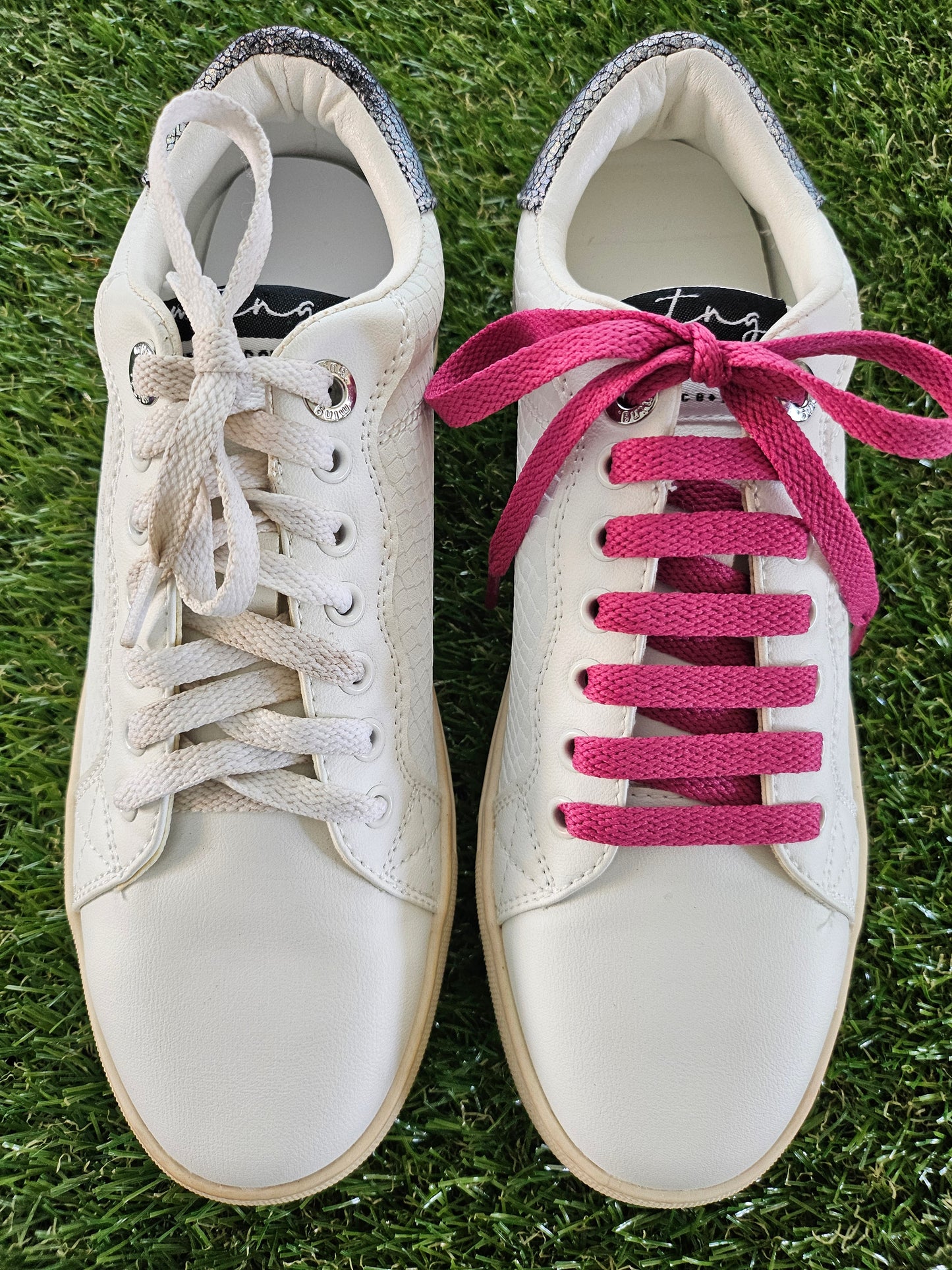 raspberry pink shoelaces in a white trainer on green grass