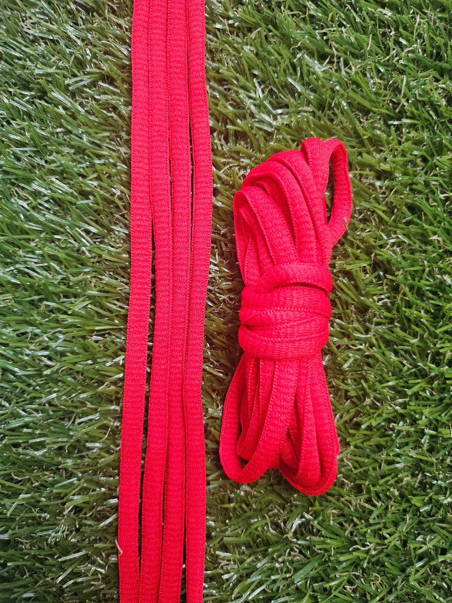Red classic oval shoelaces on green grass