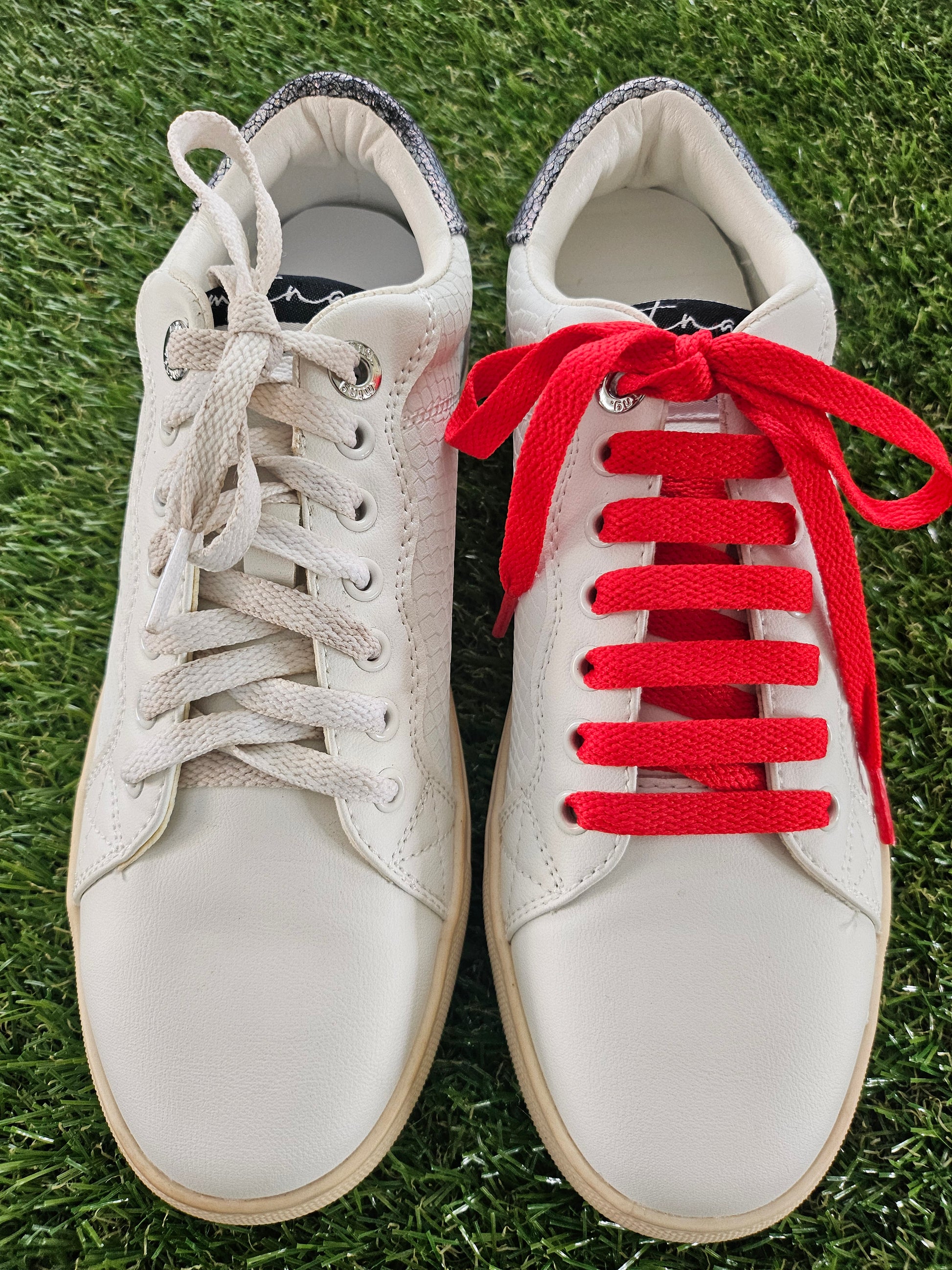 White sneakers with red and white laces on grass