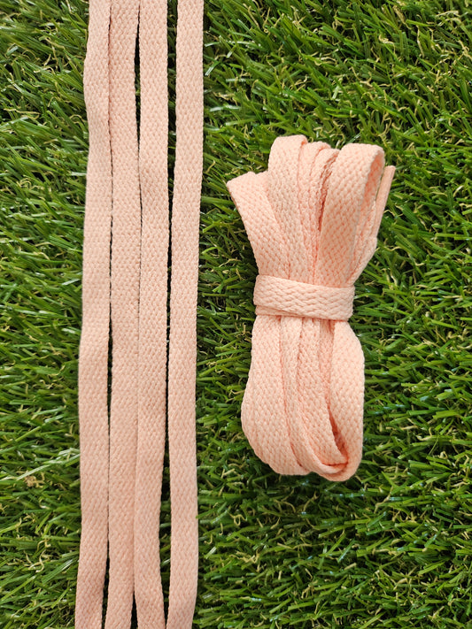 Soft peach coloured shoelaces on green grass