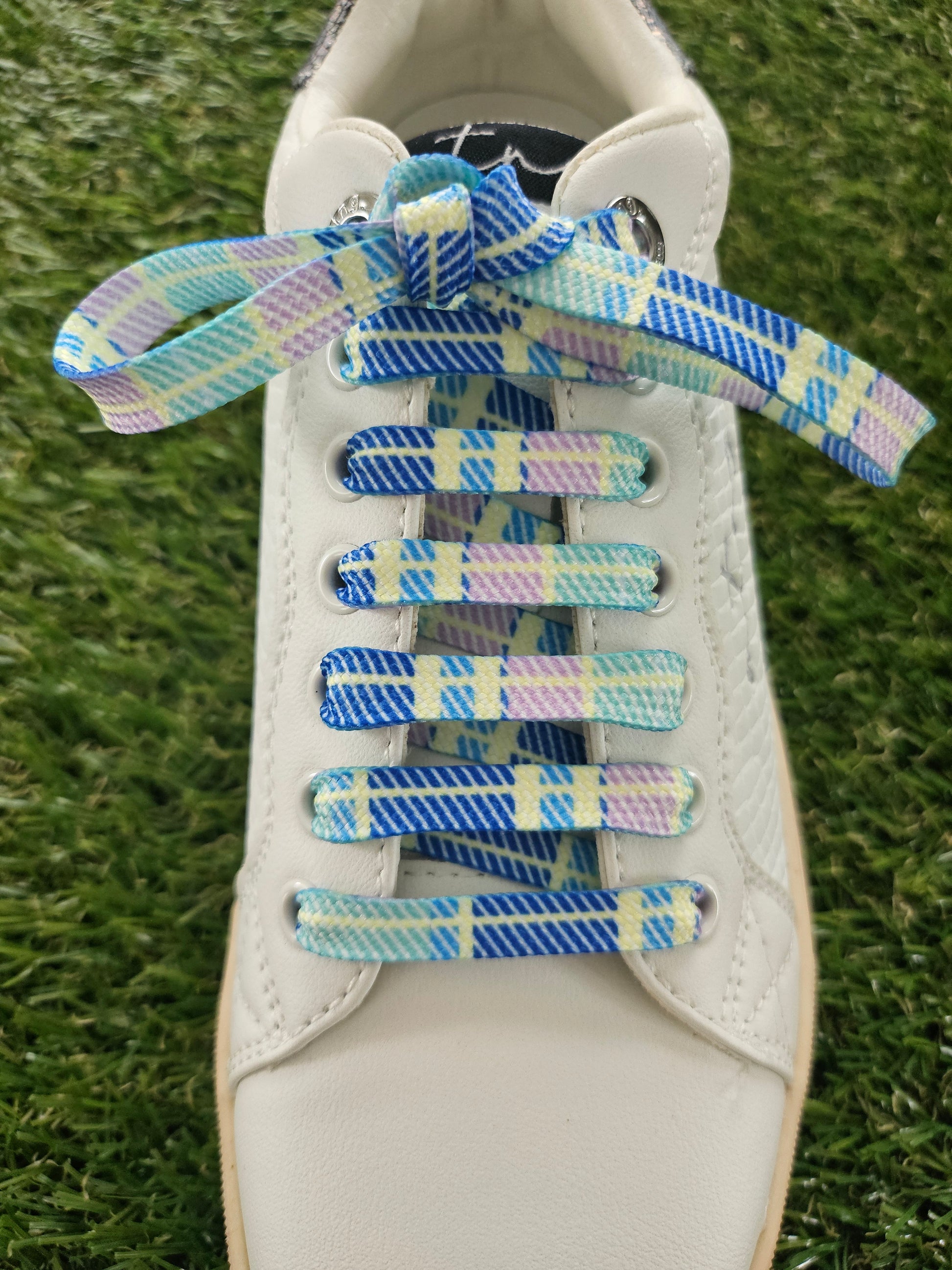 Colorful shoelaces on a white sneaker with grass in the background