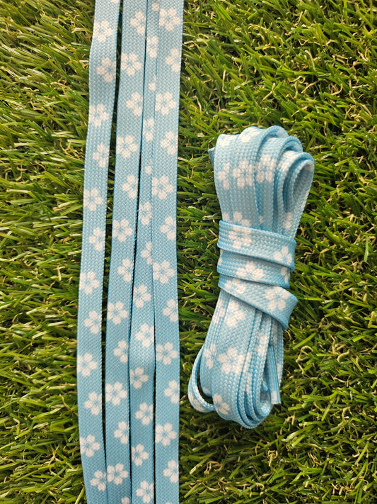 Spring Sky light blue shoelaces with white floral pattern on grass background