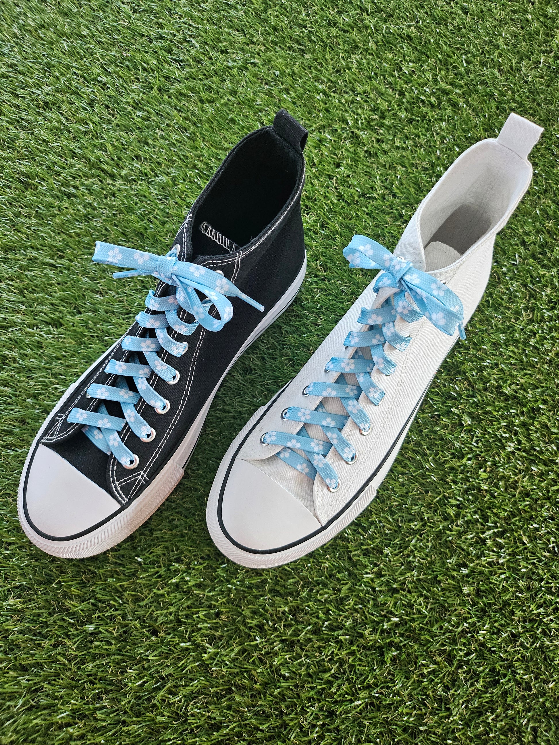 Two pairs of sneakers with blue laces on a grassy background