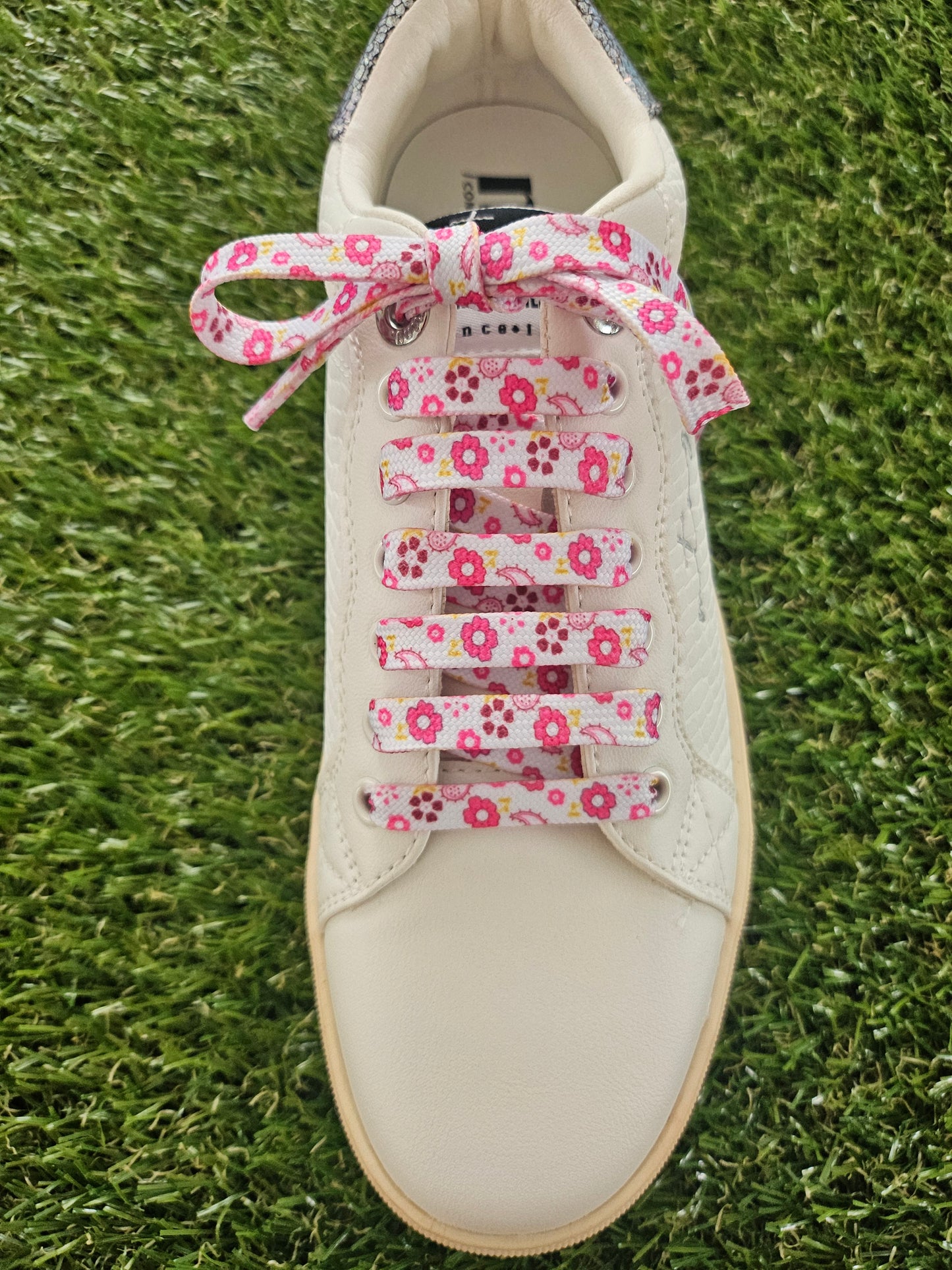 pink and yellow flowered shoelaces in a white trainer