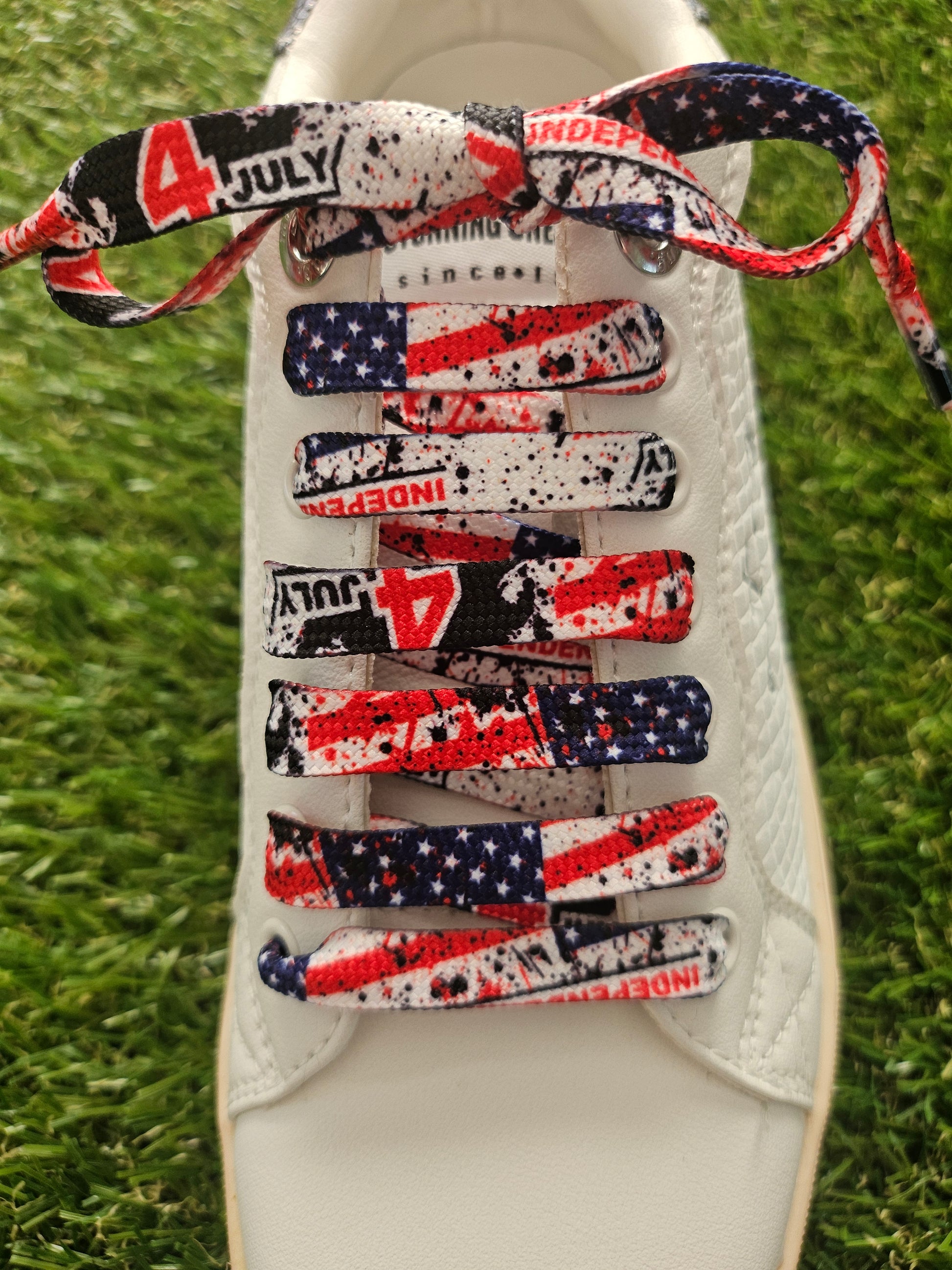 usa flag detailed shoelaces on a white trainer on green grass