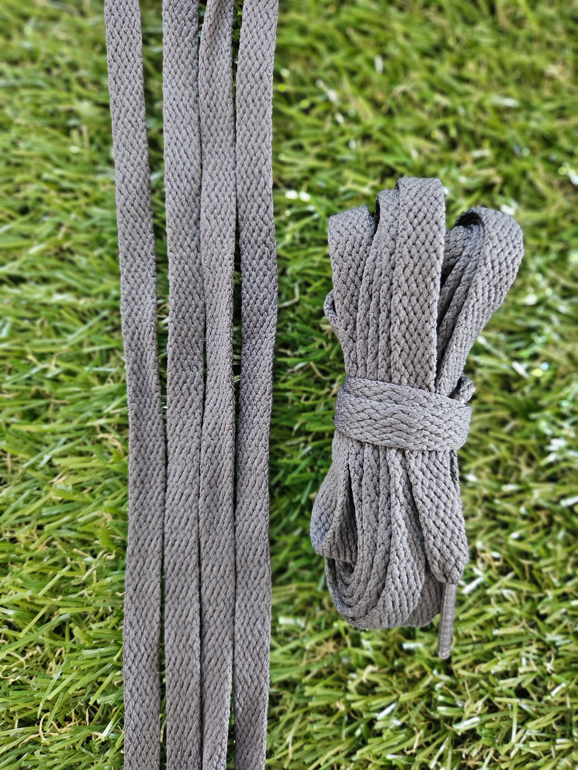 Dark grey shoelaces on green grass