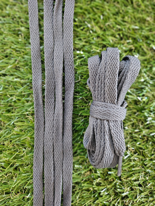 Dark grey shoelaces on green grass