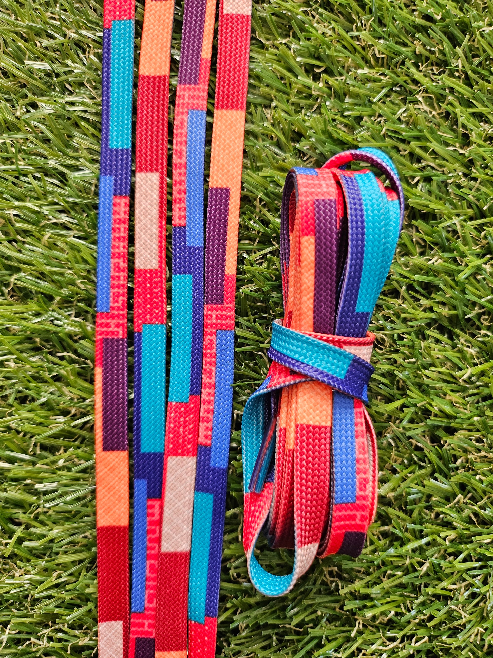 Geometric patterned shoelaces lying on green grass