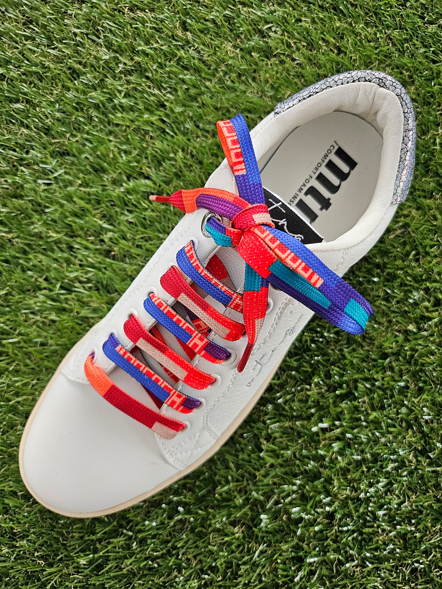 White shoe with colourful laces on grass