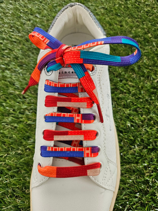 Colourful mosaic shoelaces on a white sneaker with grass background