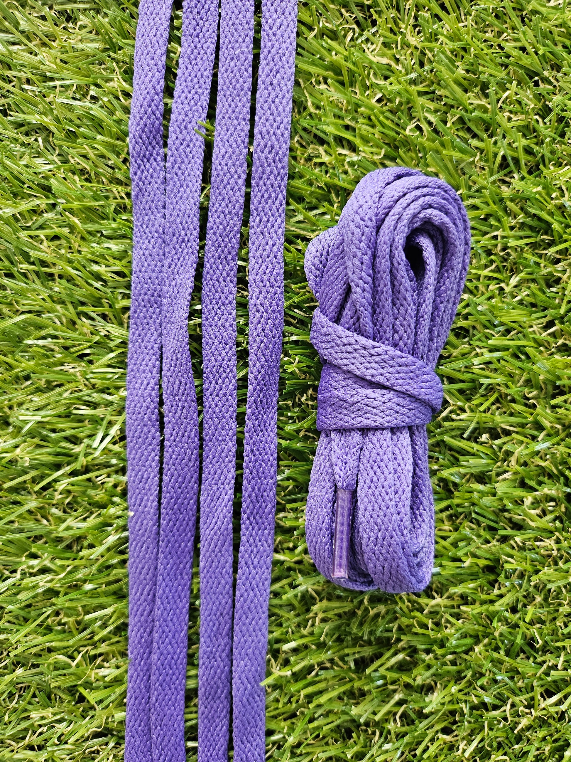 Violet coloured shoelaces on green grass