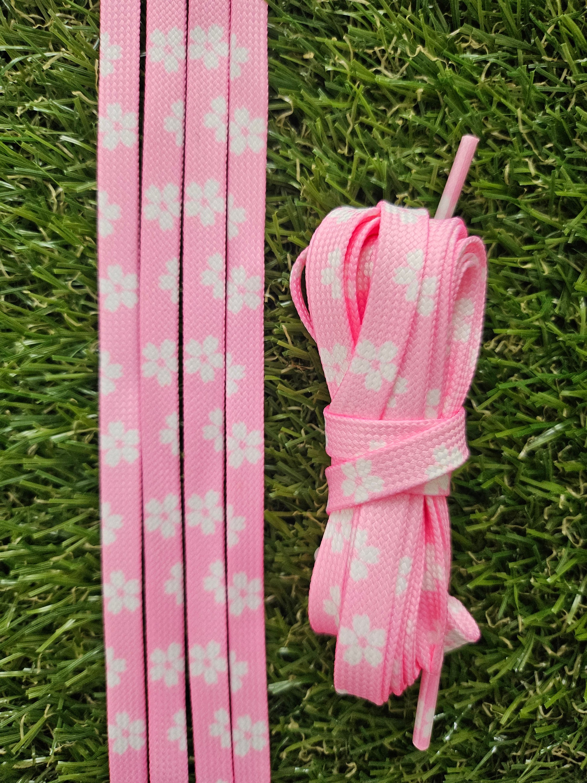 Pink shoelaces with white floral pattern on grass