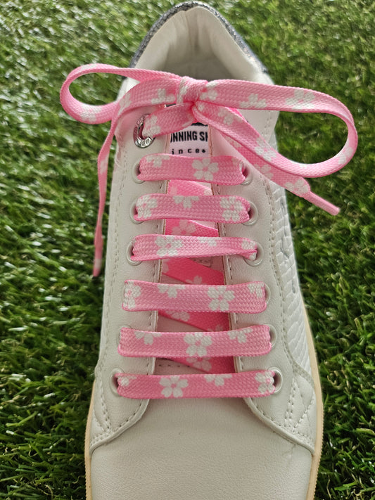 White sneaker with pink floral lace on a grass background