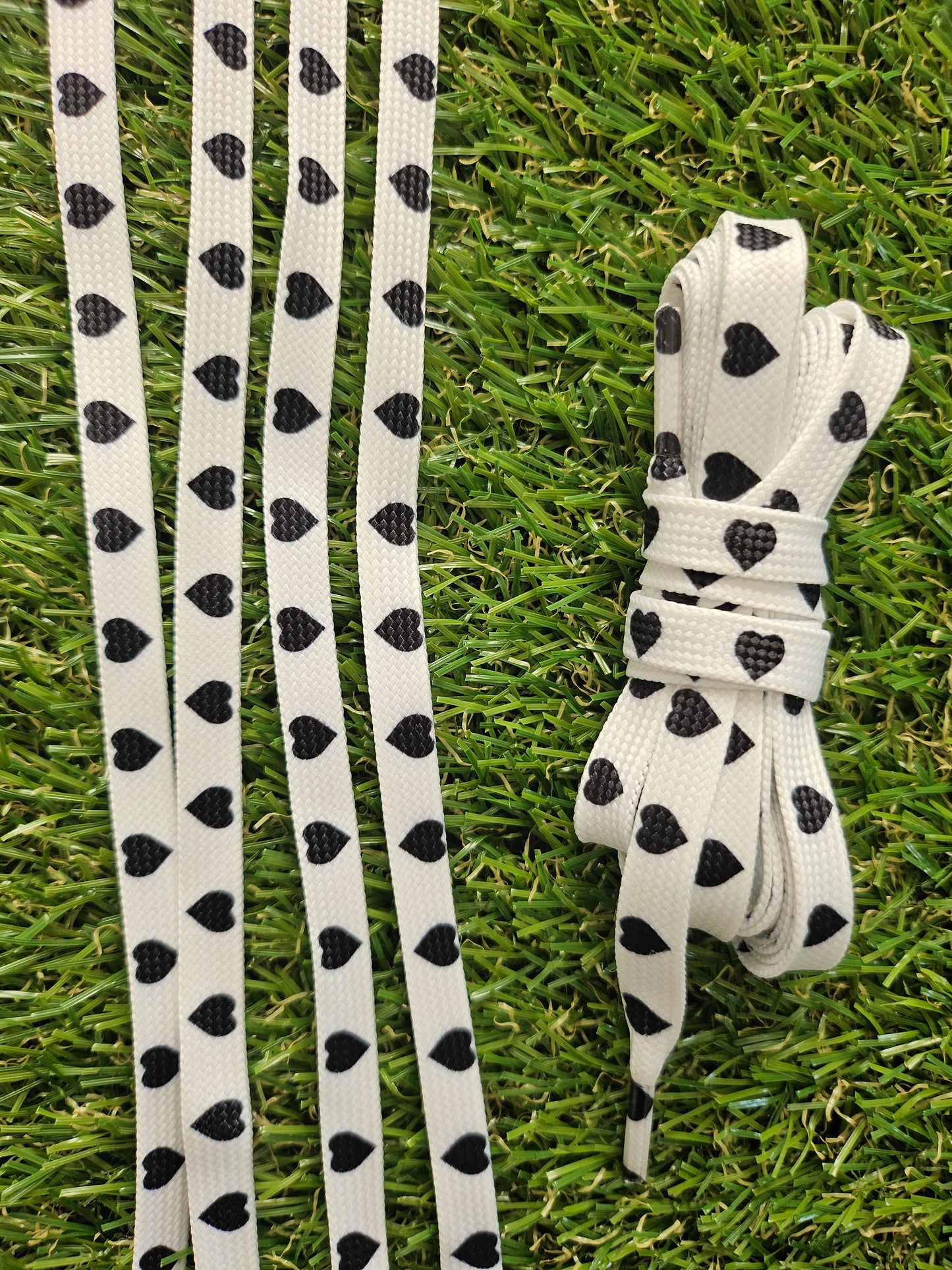 White shoelaces with black heart patterns on grass