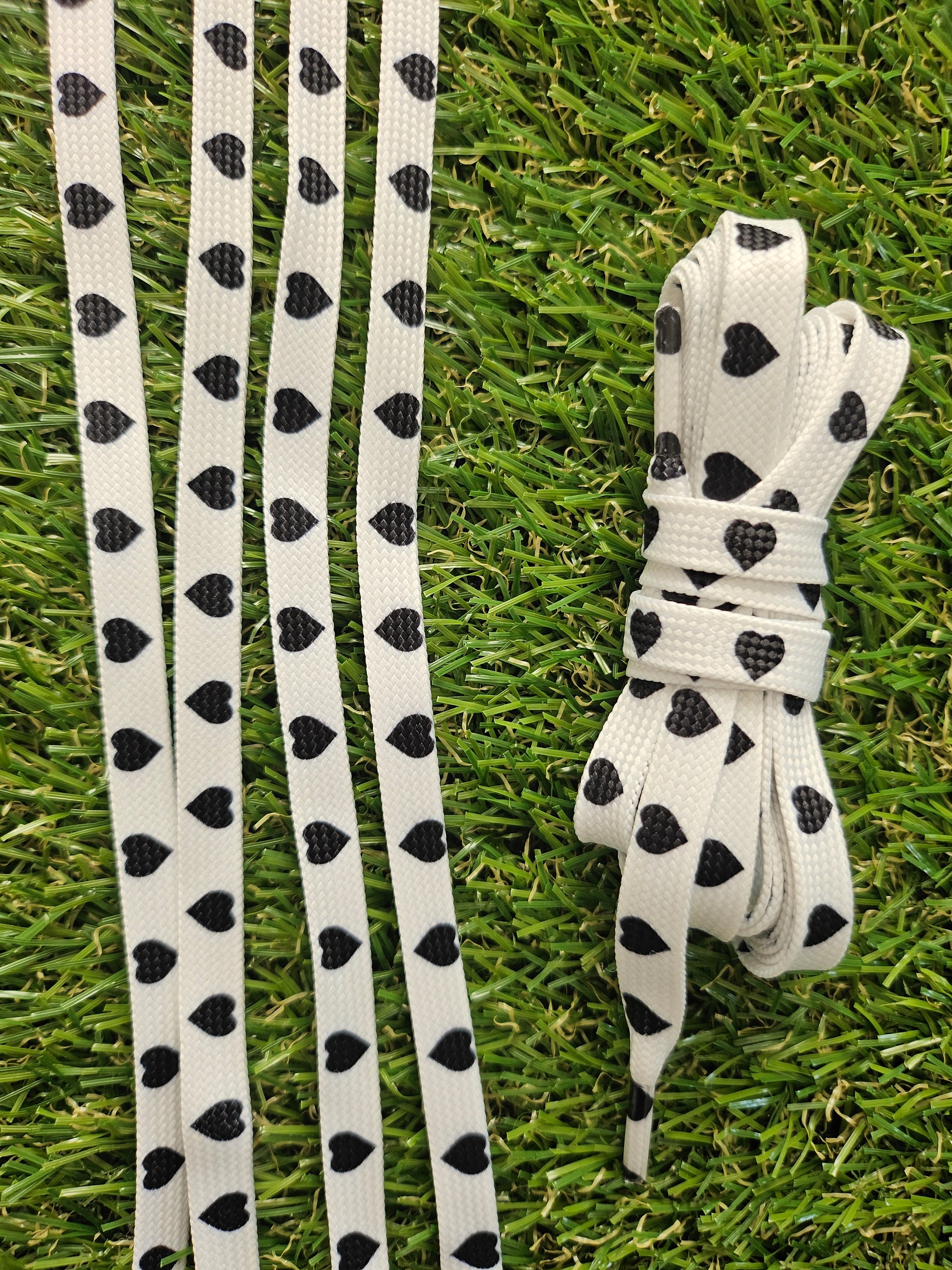 White shoelaces with black heart patterns on grass