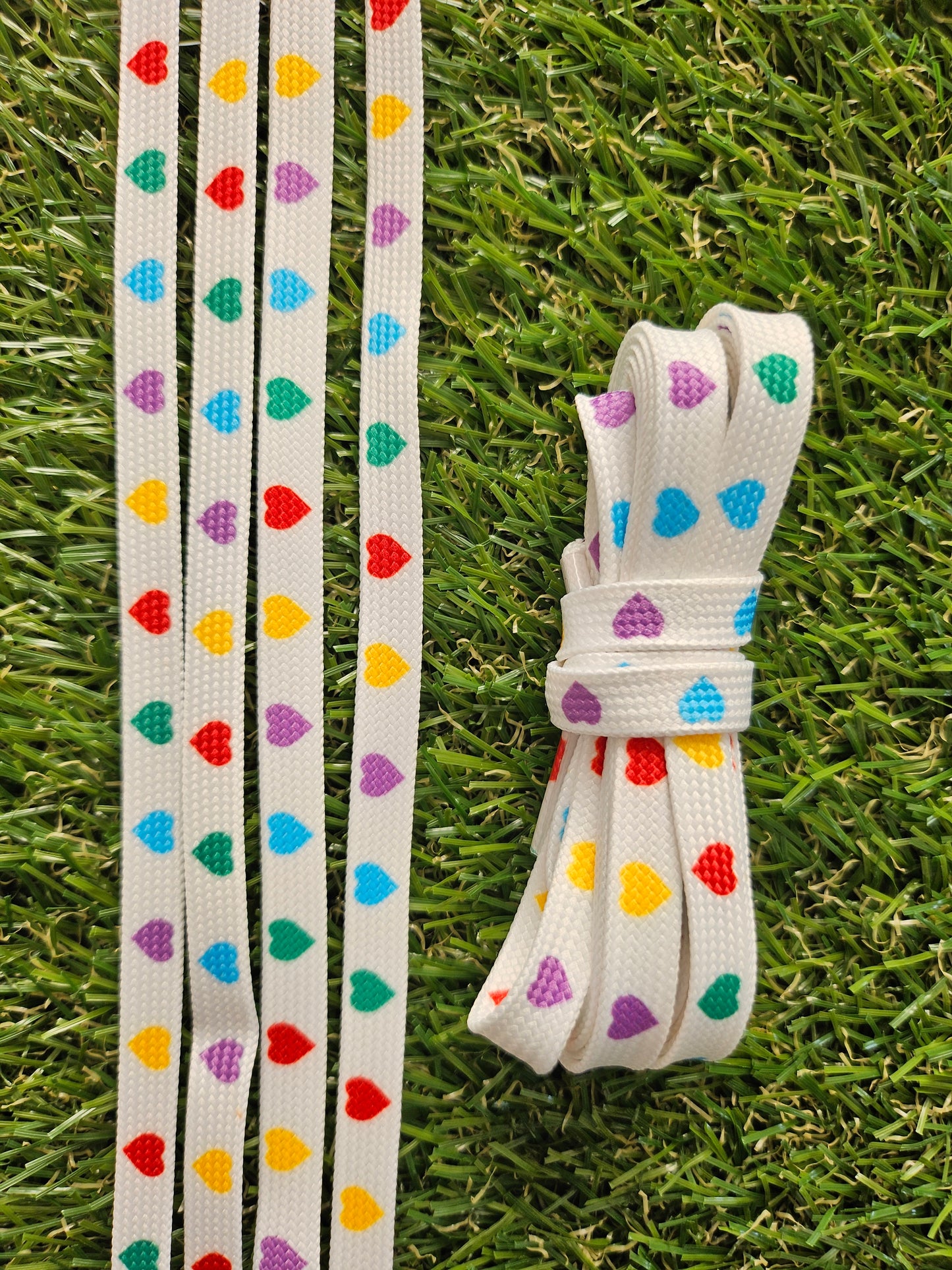 Colorful heart-patterned shoelaces on a grass background