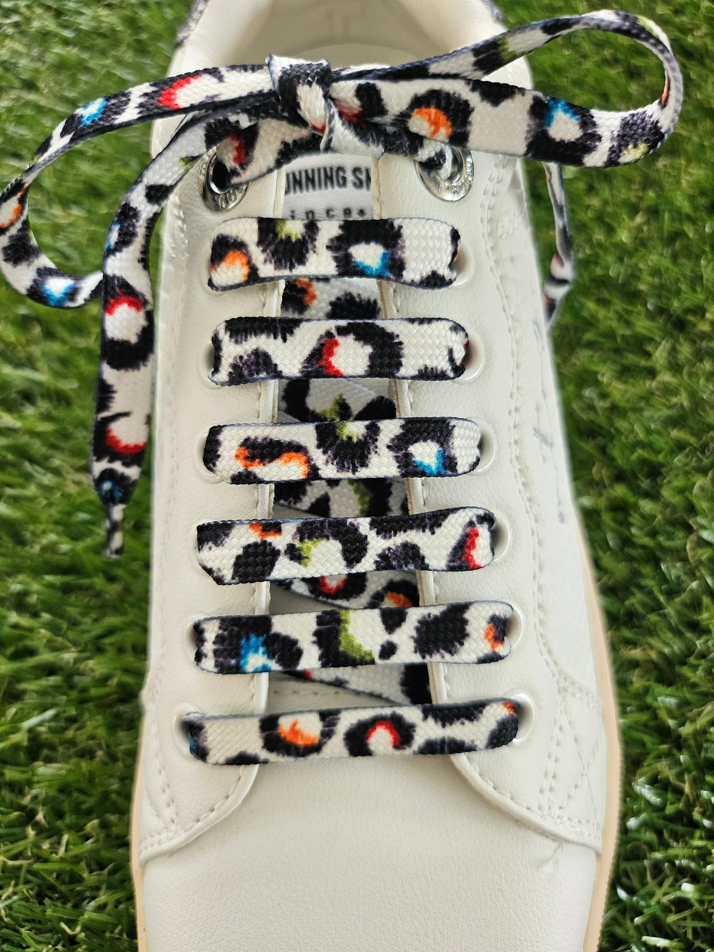 Shoe with colorful leopard print laces on a grass background