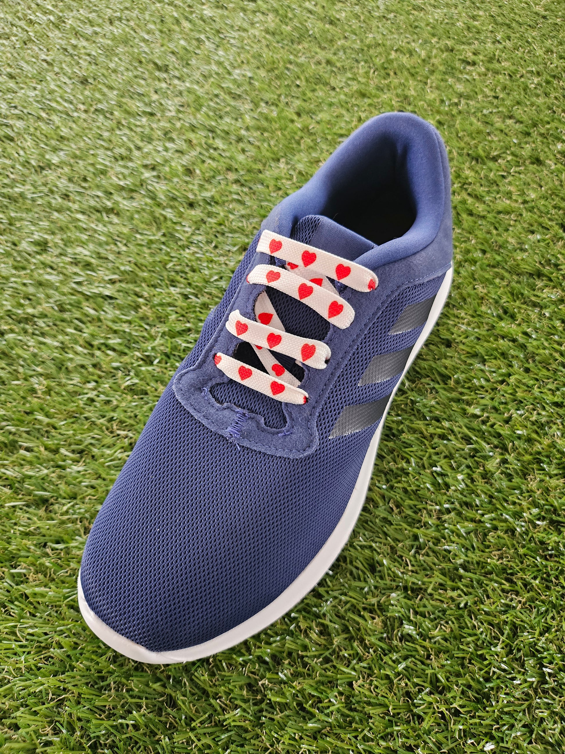 Blue shoe with red and white love heart laces on grass
