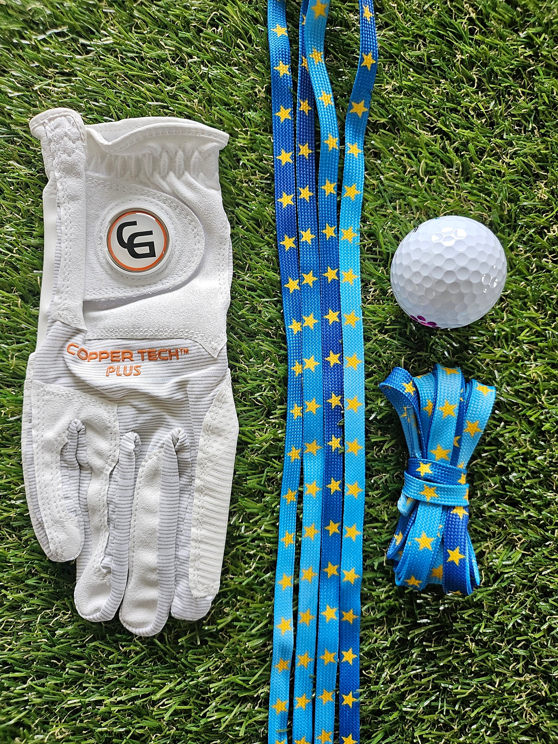 Golf glove, golf ball, and blue laces with yellow stars on grass