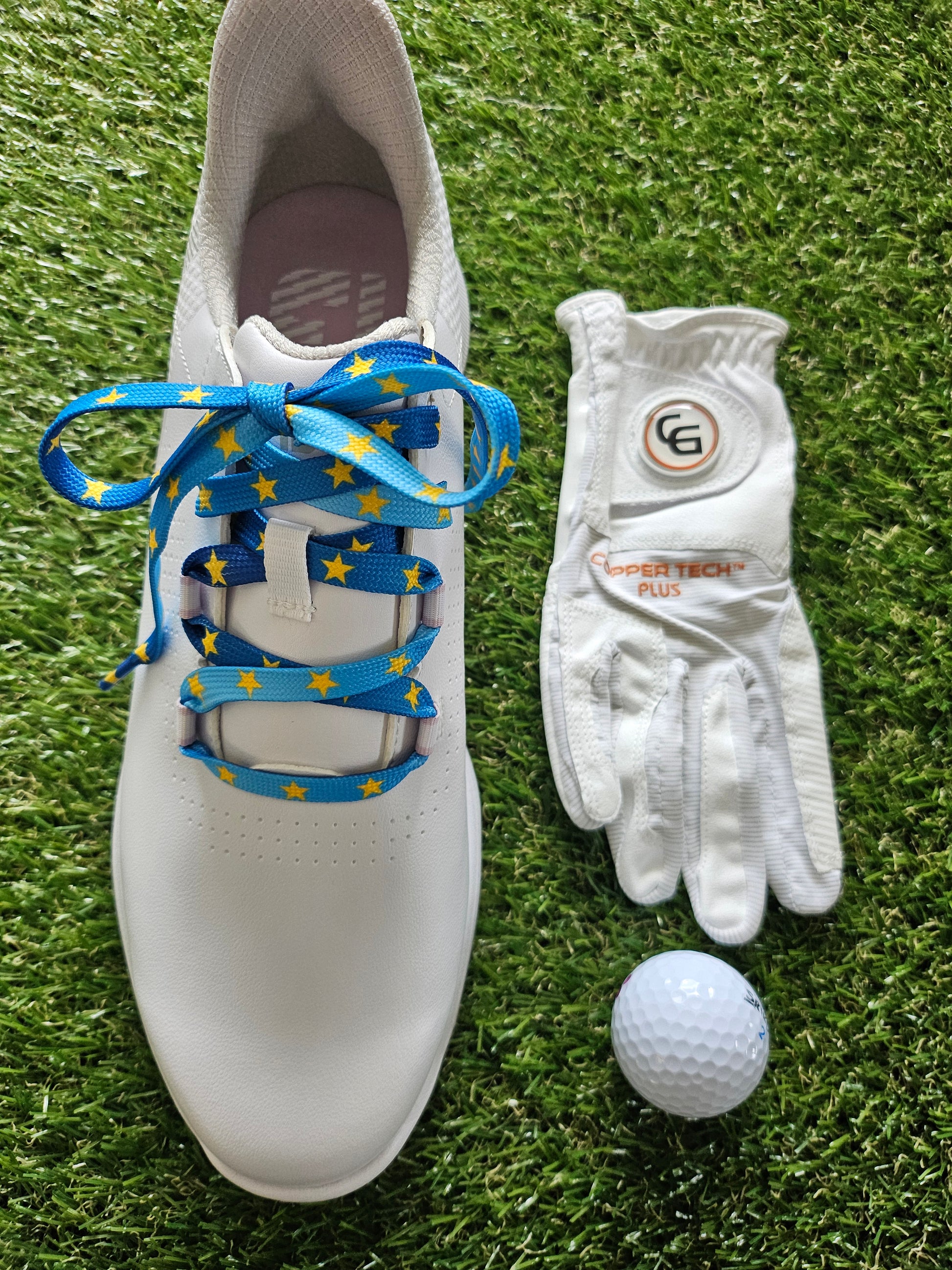 White golf shoe with blue laces, white glove, and golf ball on grass