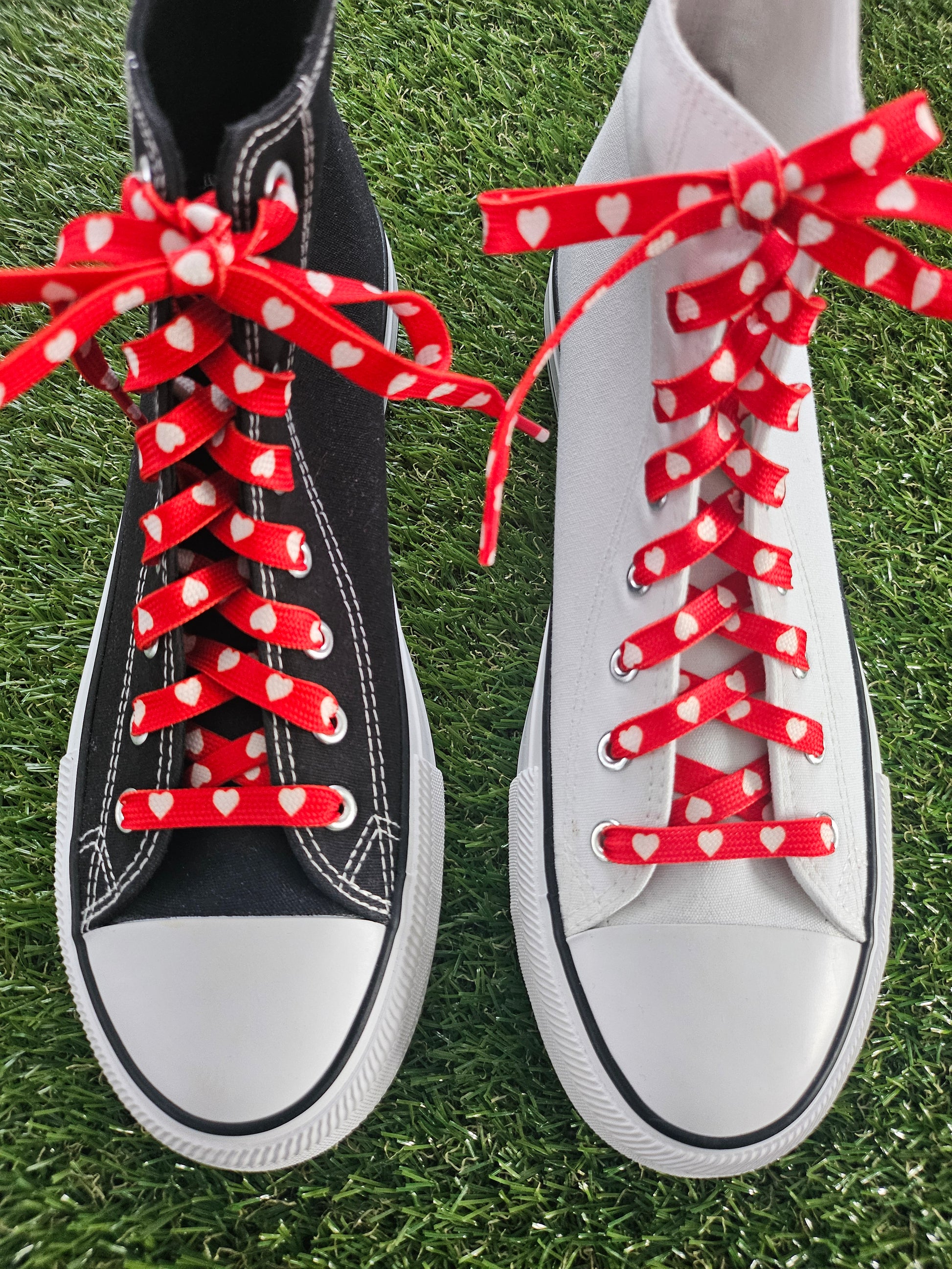 White and black sneakers with red polka dot laces on grass