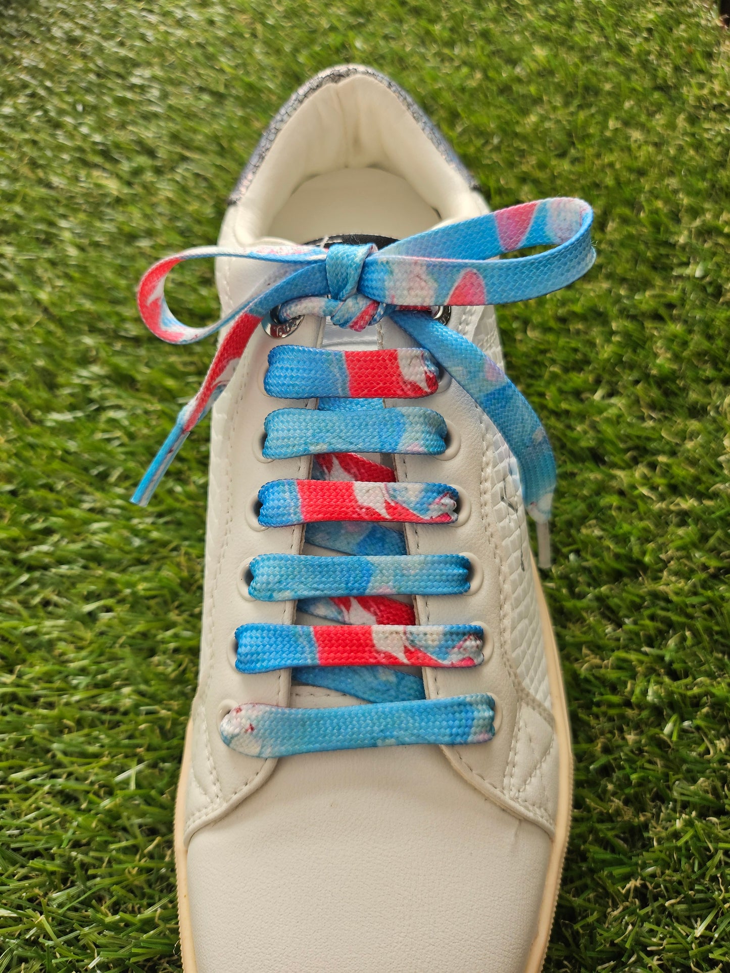 Shoe with colorful laces on a grass background