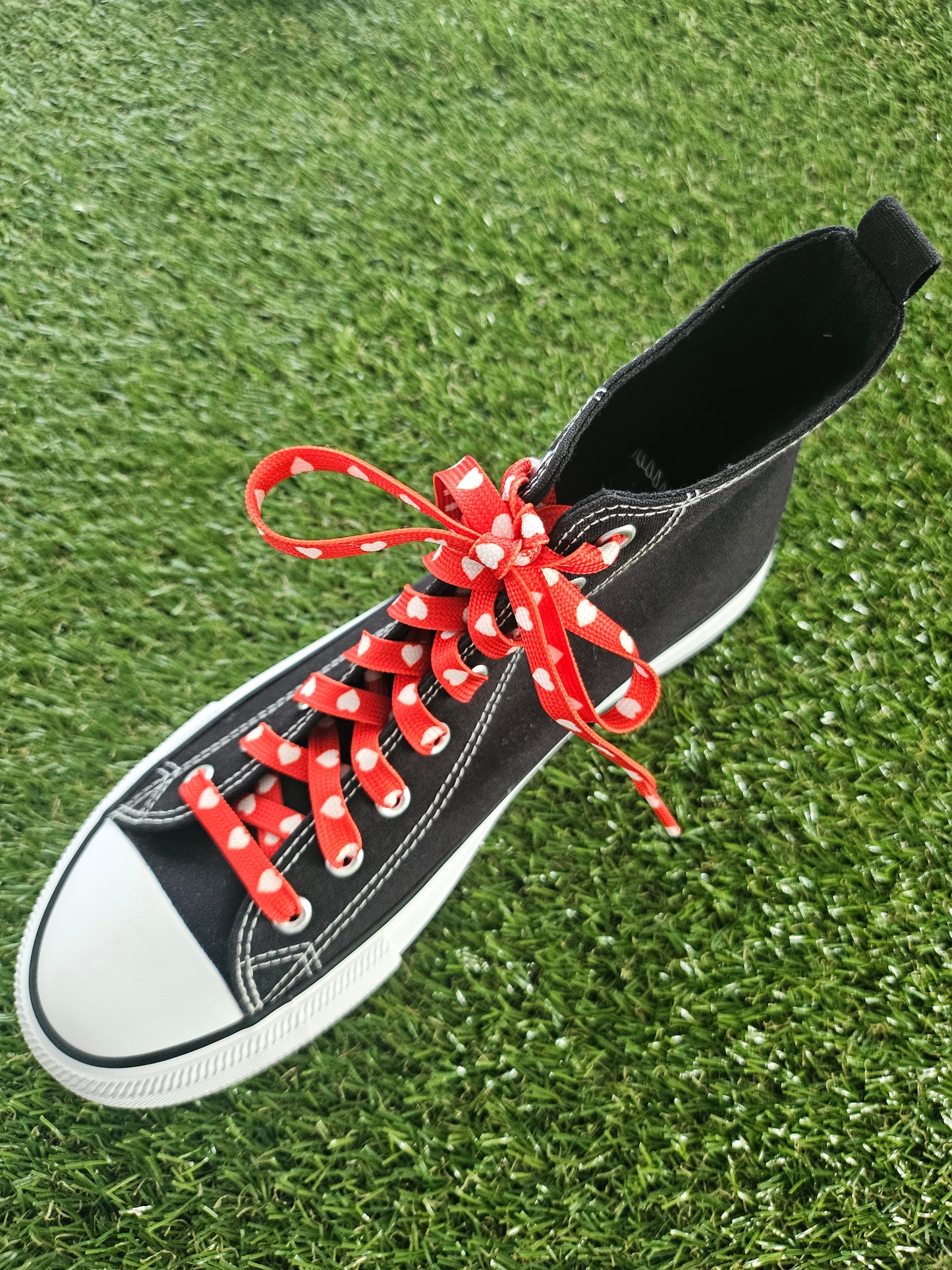 Black sneaker with red laces on a grassy background