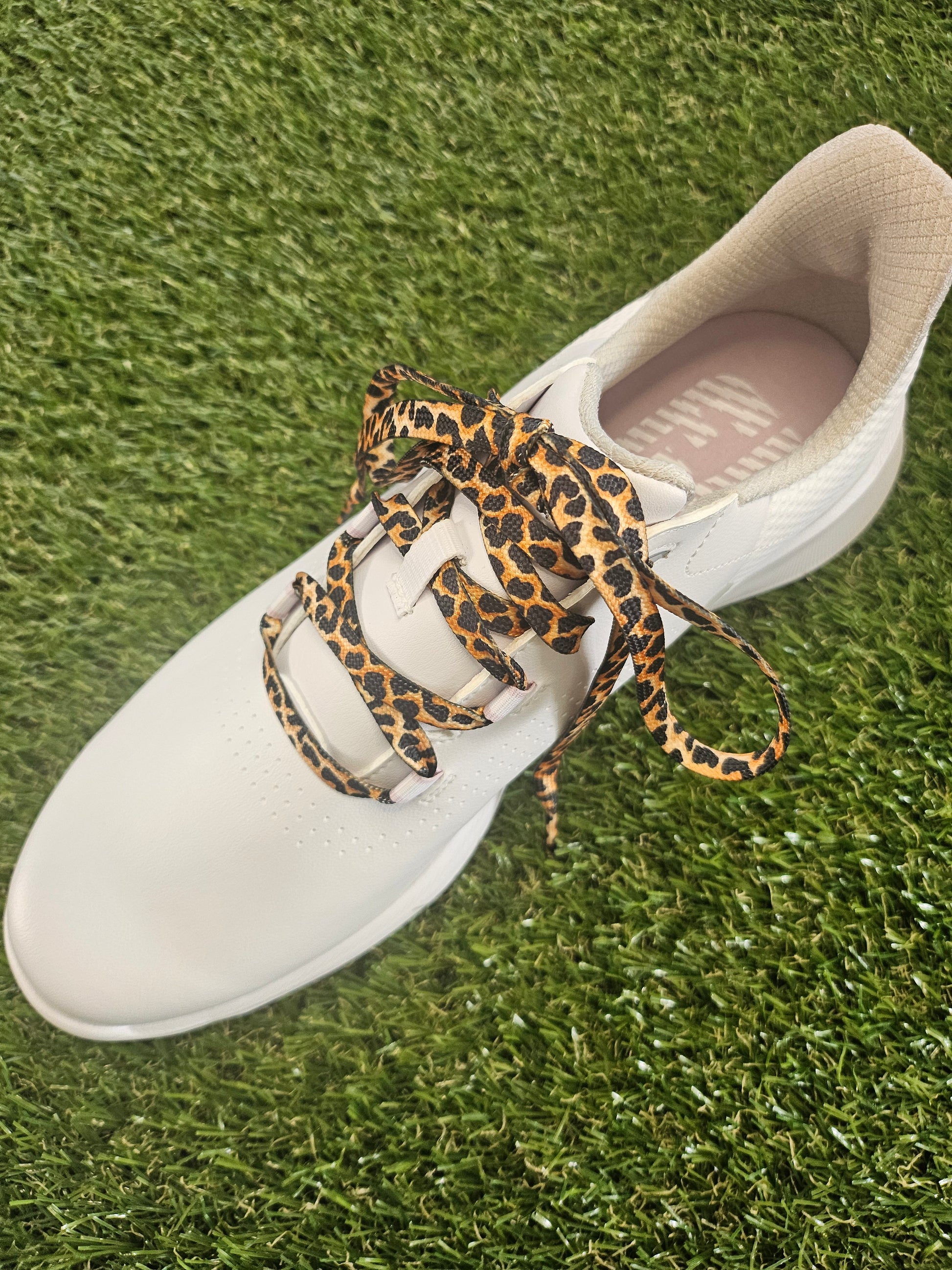 White golf shoe with leopard print shoelace on grass