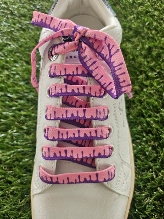 White sneaker with pink and purple tie-dye laces on a grass background