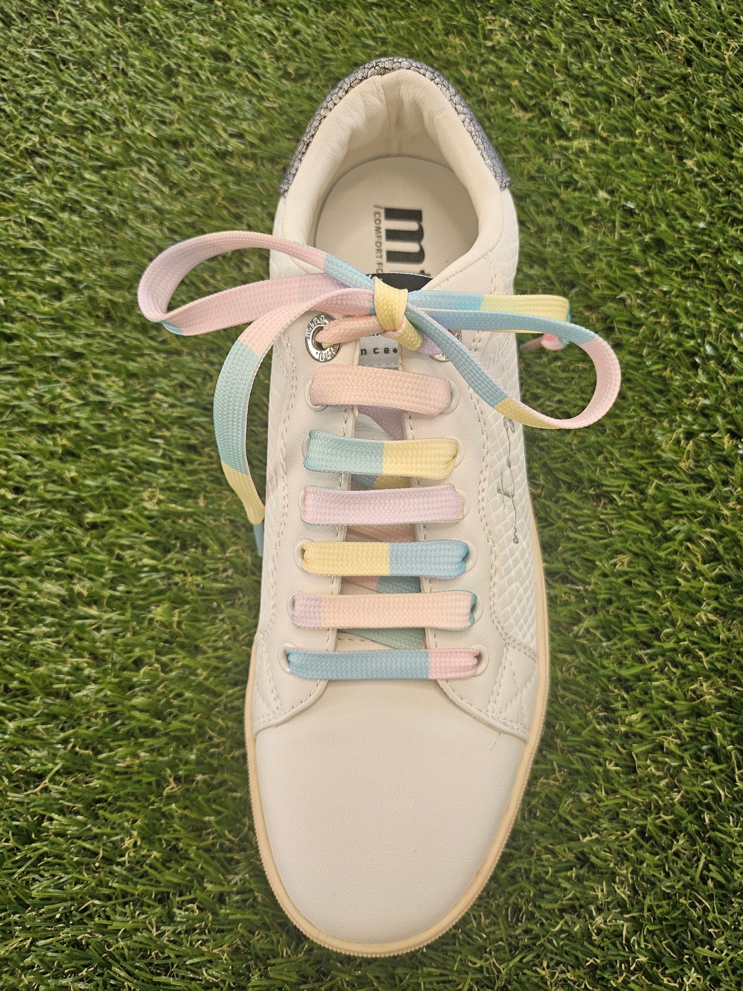 White trainer with pastel shoelaces on grass