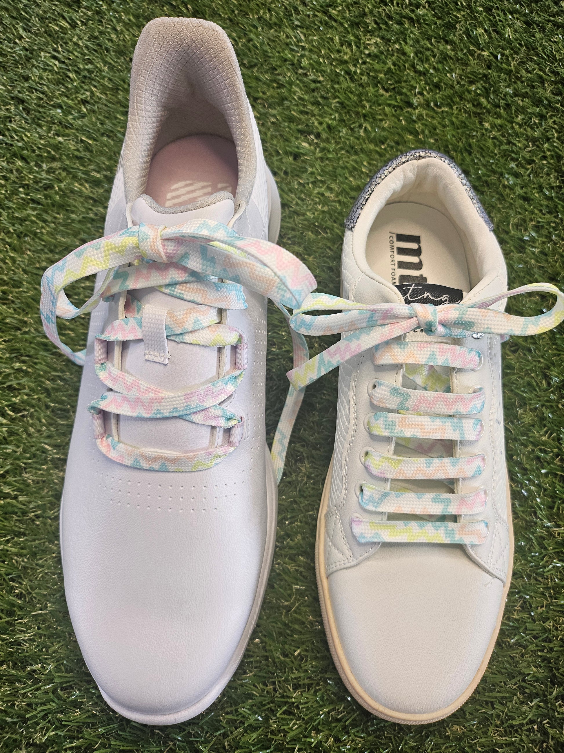 White ladies casual shoes with colourful  pastel laces on a grassy background