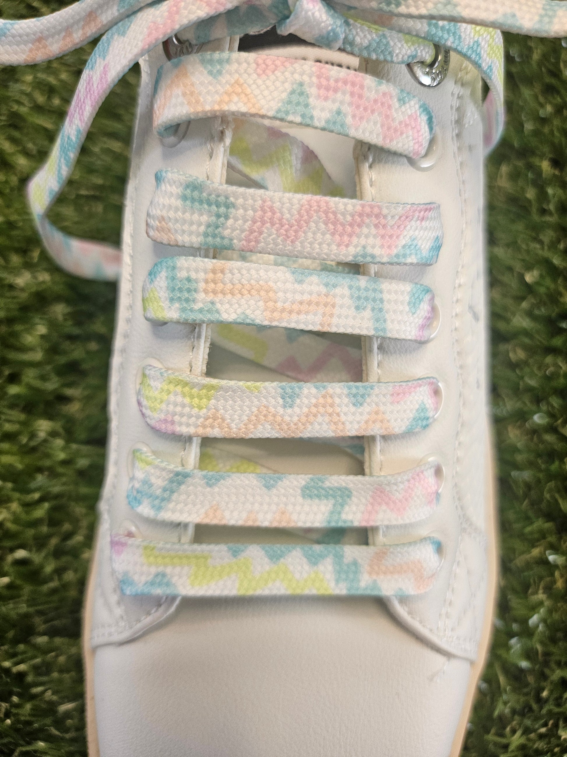 Pastel zigzag patterned trainer shoelaces laid flat and styled in a white trainer