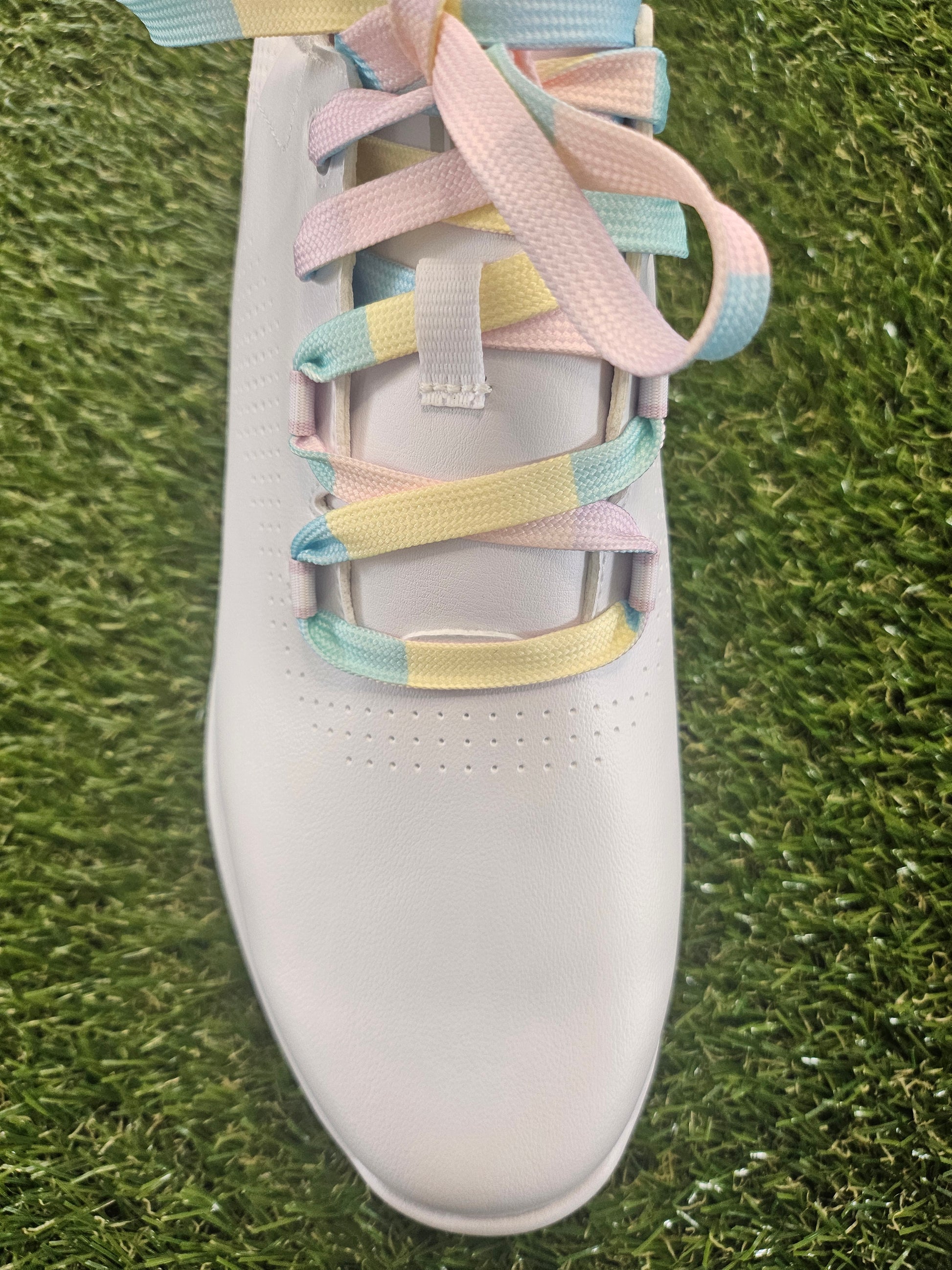 White ladies golf shoe with colourful laces on a grass background
