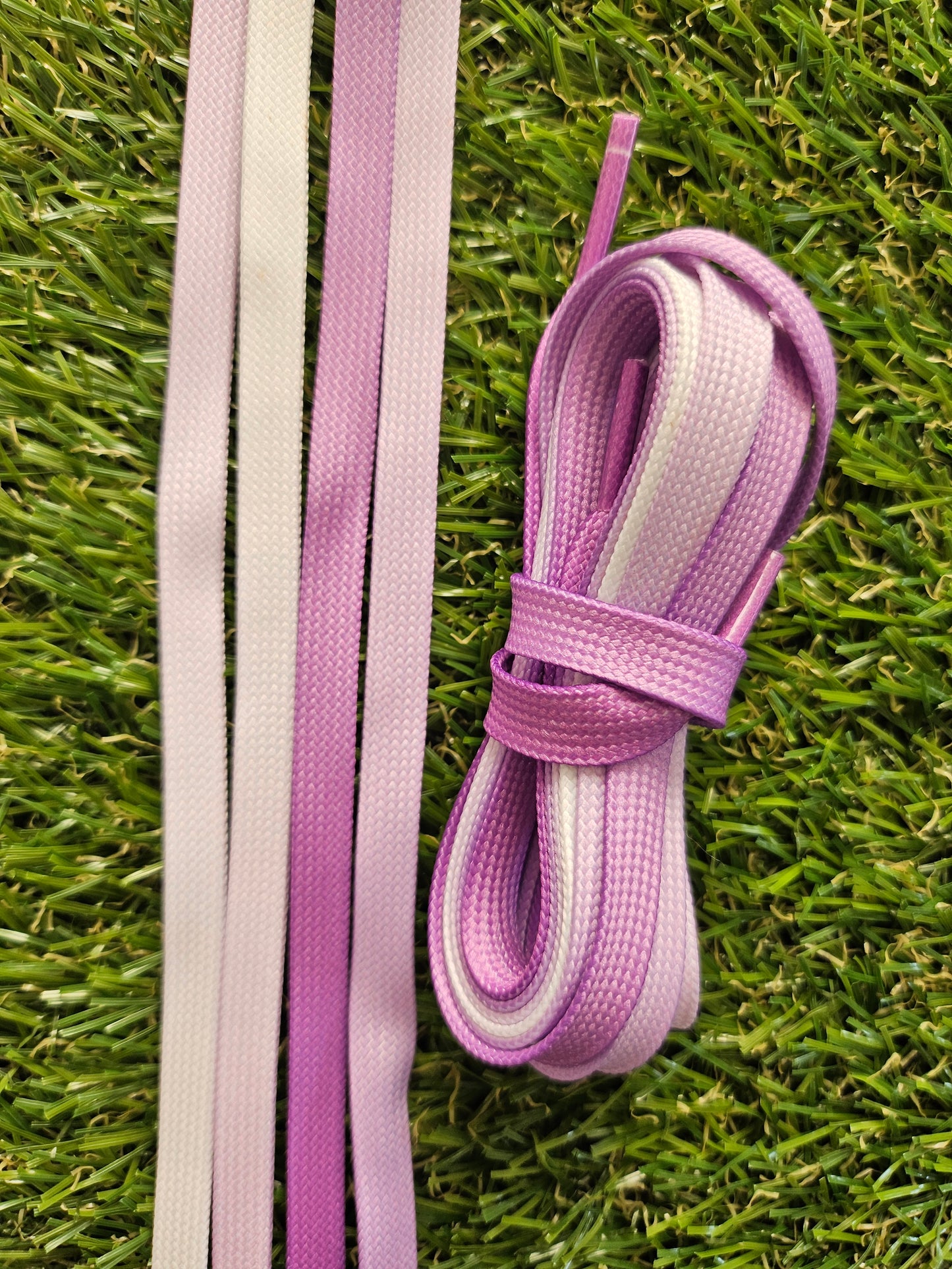 Purple and white fade shoelaces on grass