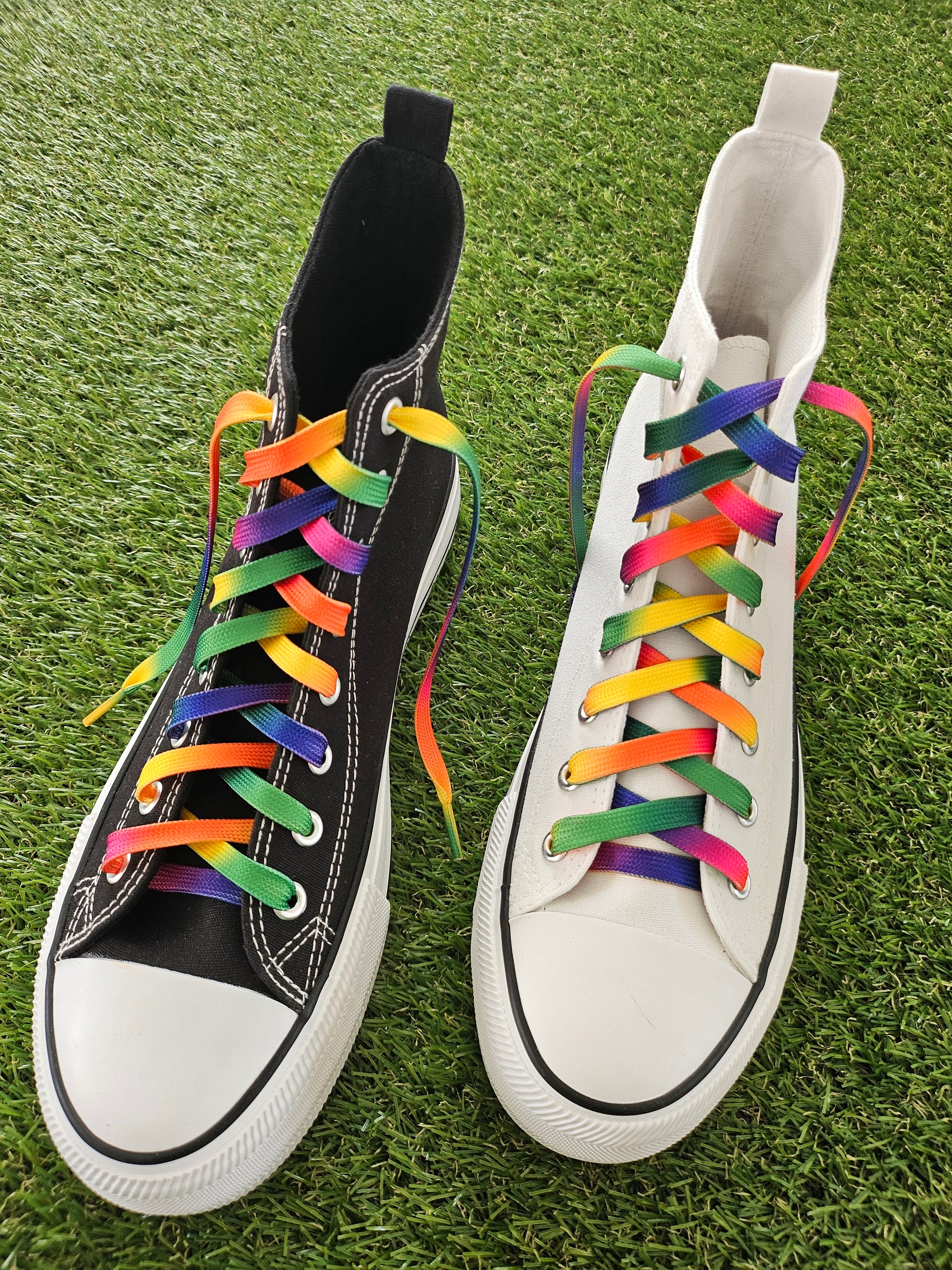 Pair of trainers with colourful rainbow laces on a grass background
