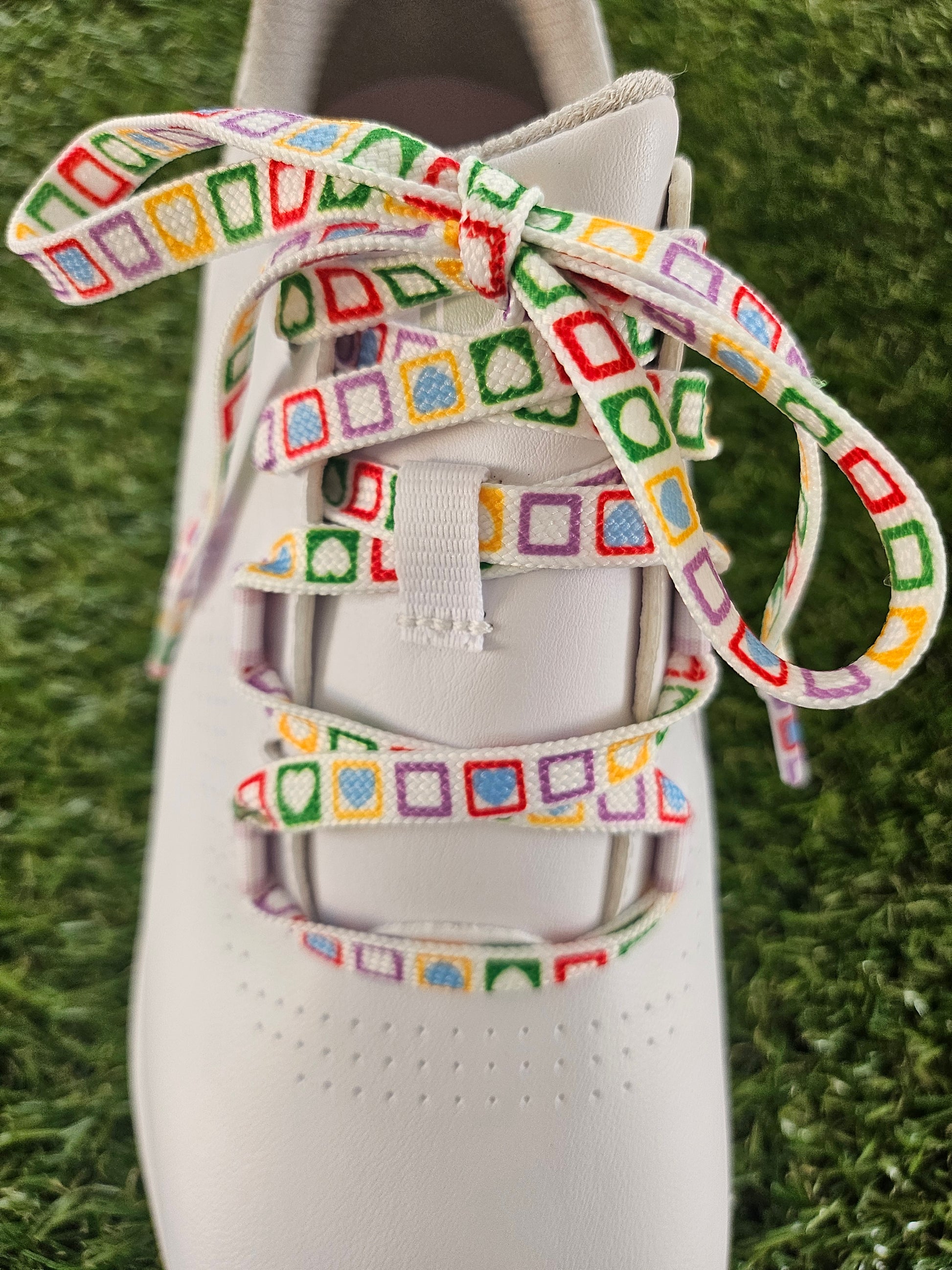 Colourful geometric shoelaces laid on grass for trainers and golf shoes