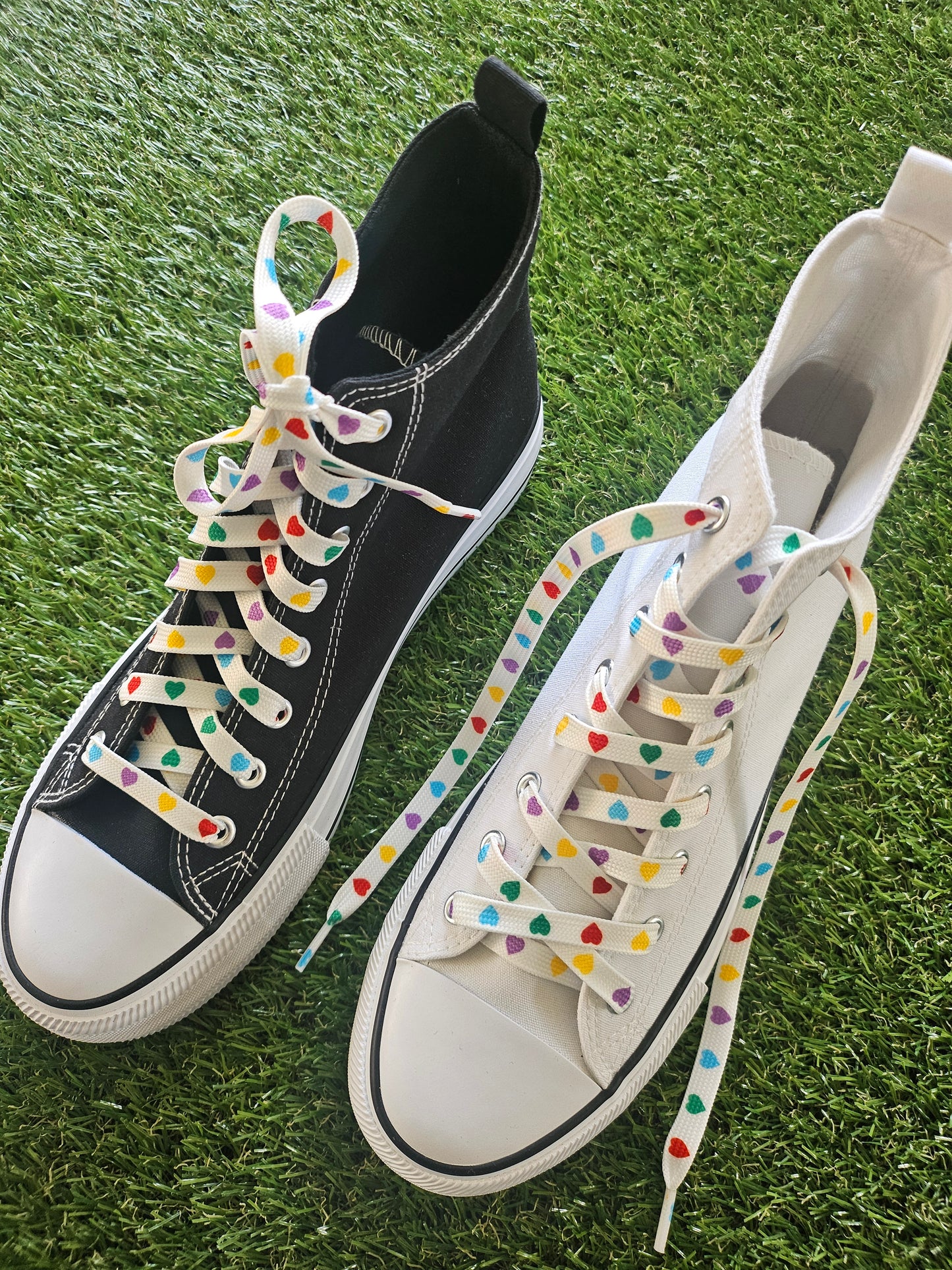 Black and white sneakers with colorful shoelaces on a grassy background