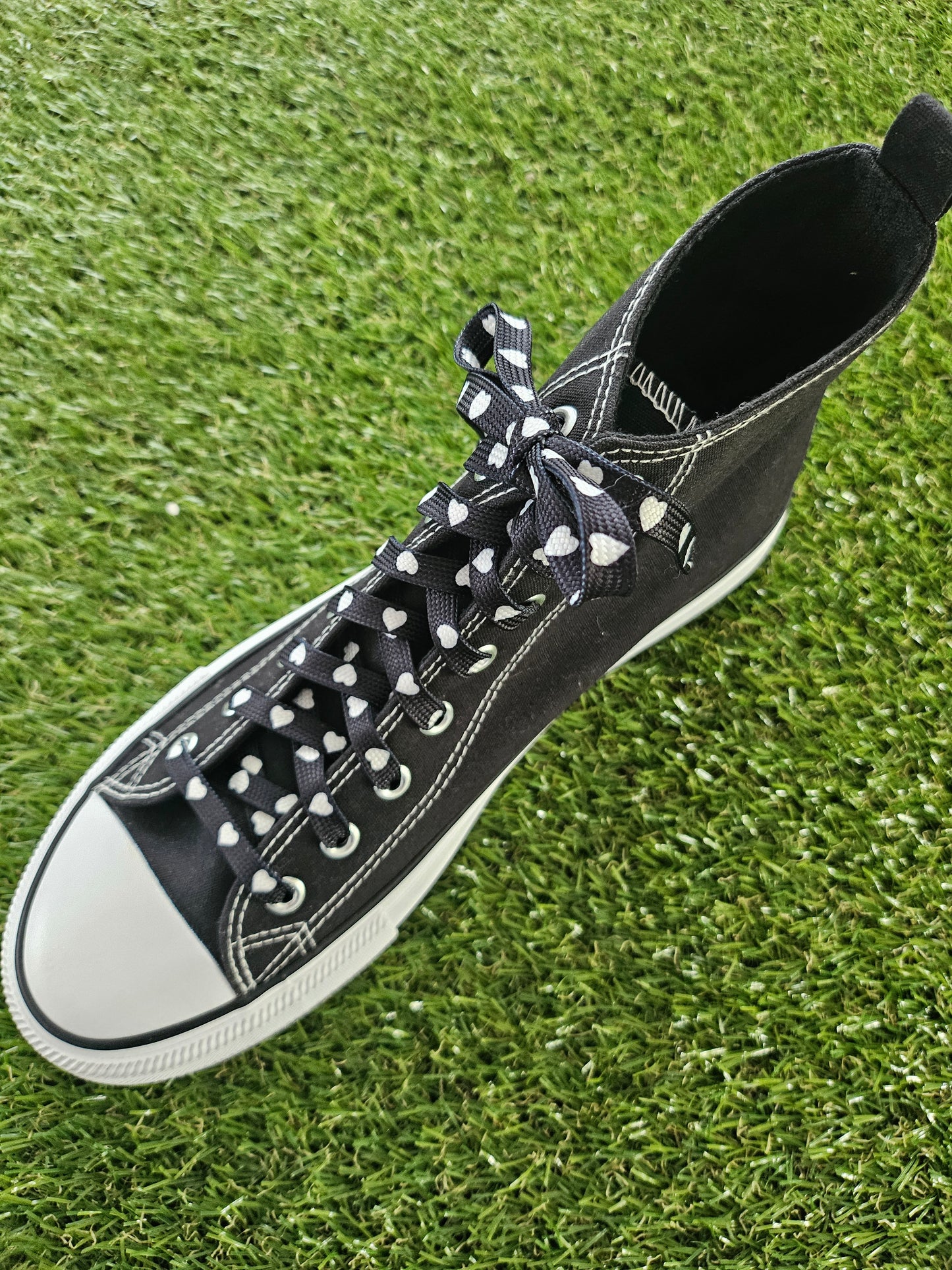 Black sneaker with white sole on a grass background