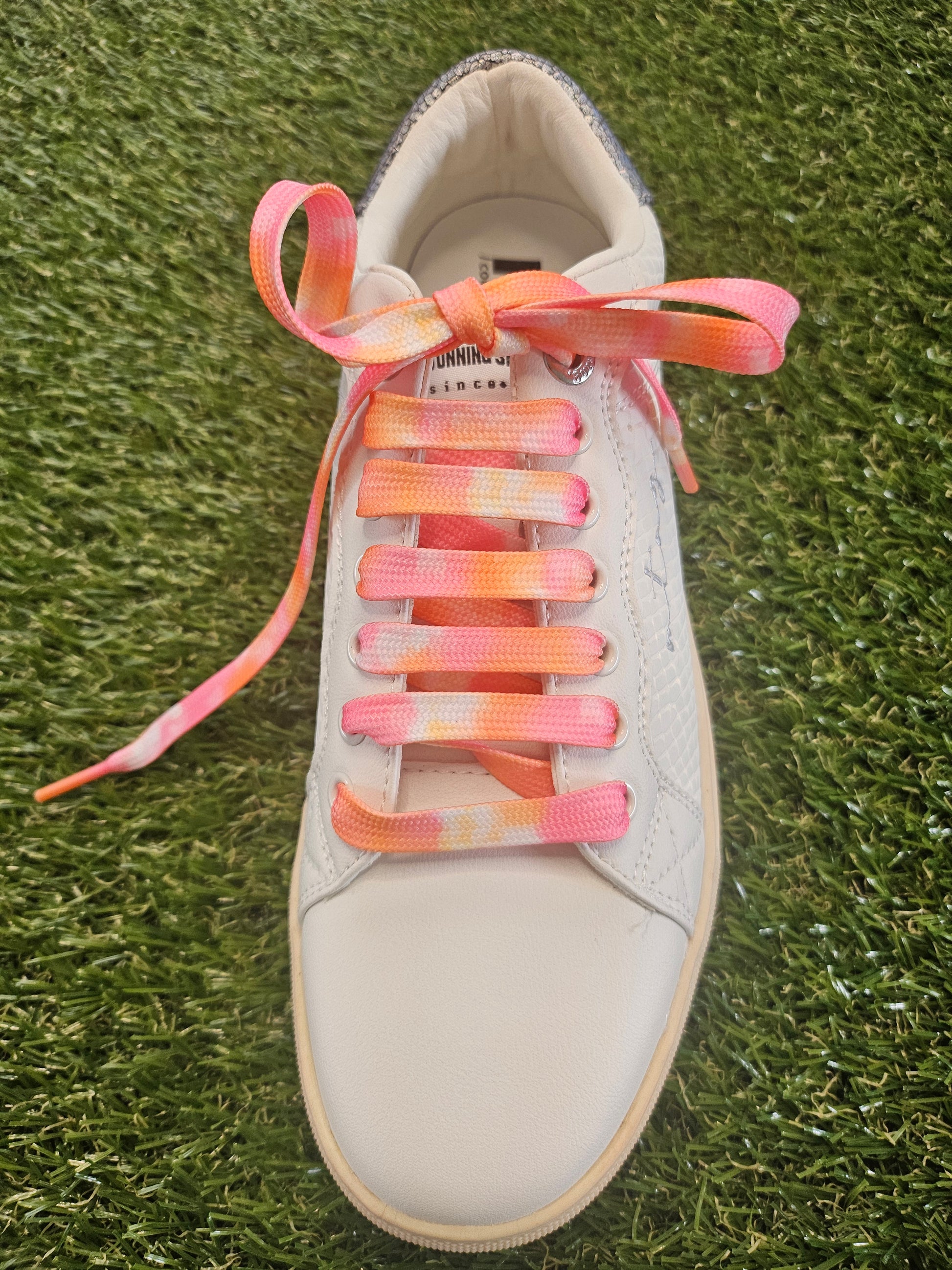 White sneaker with colourful sunset laces on grass