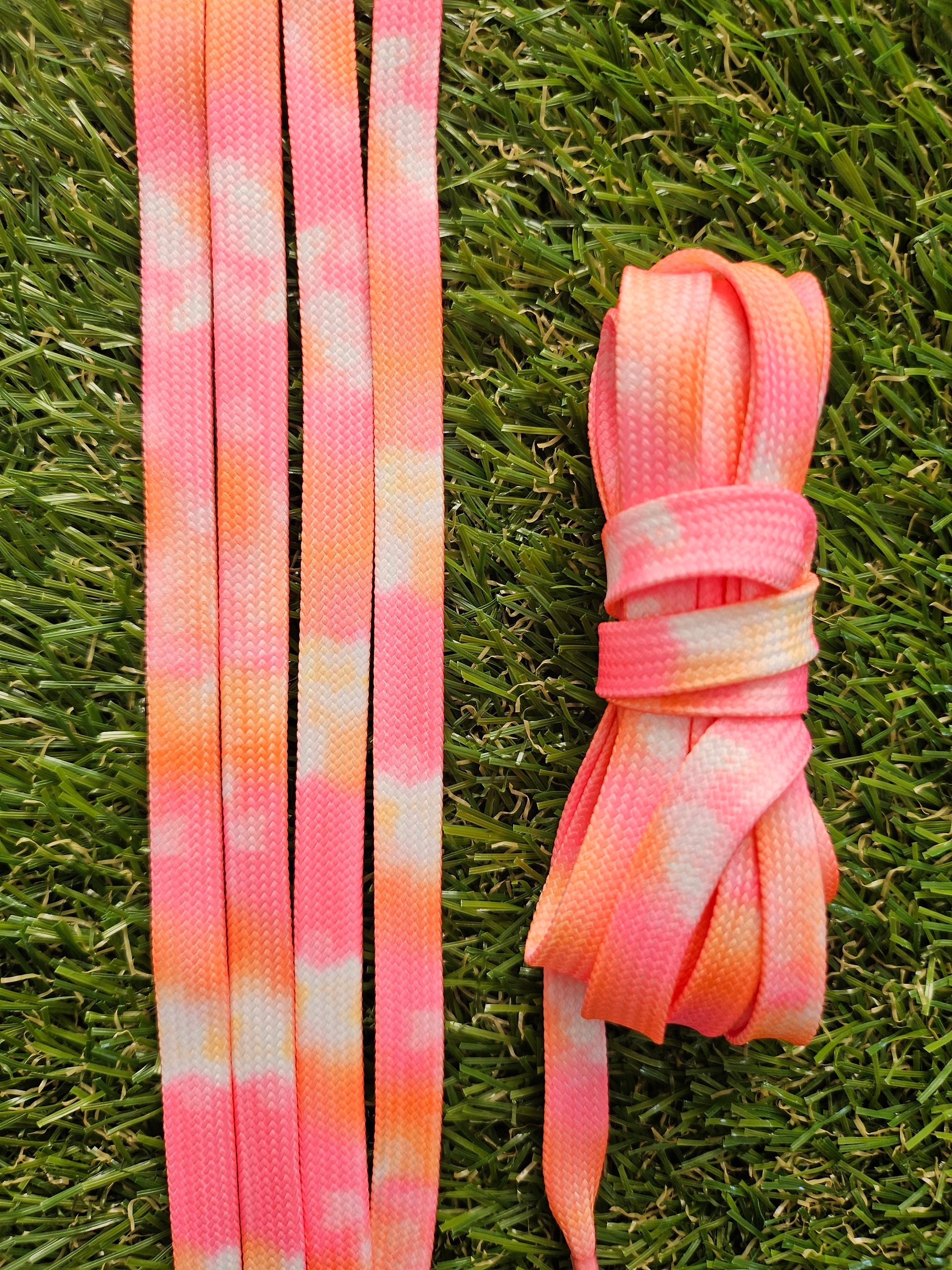 Pink and orange shoelaces on grass