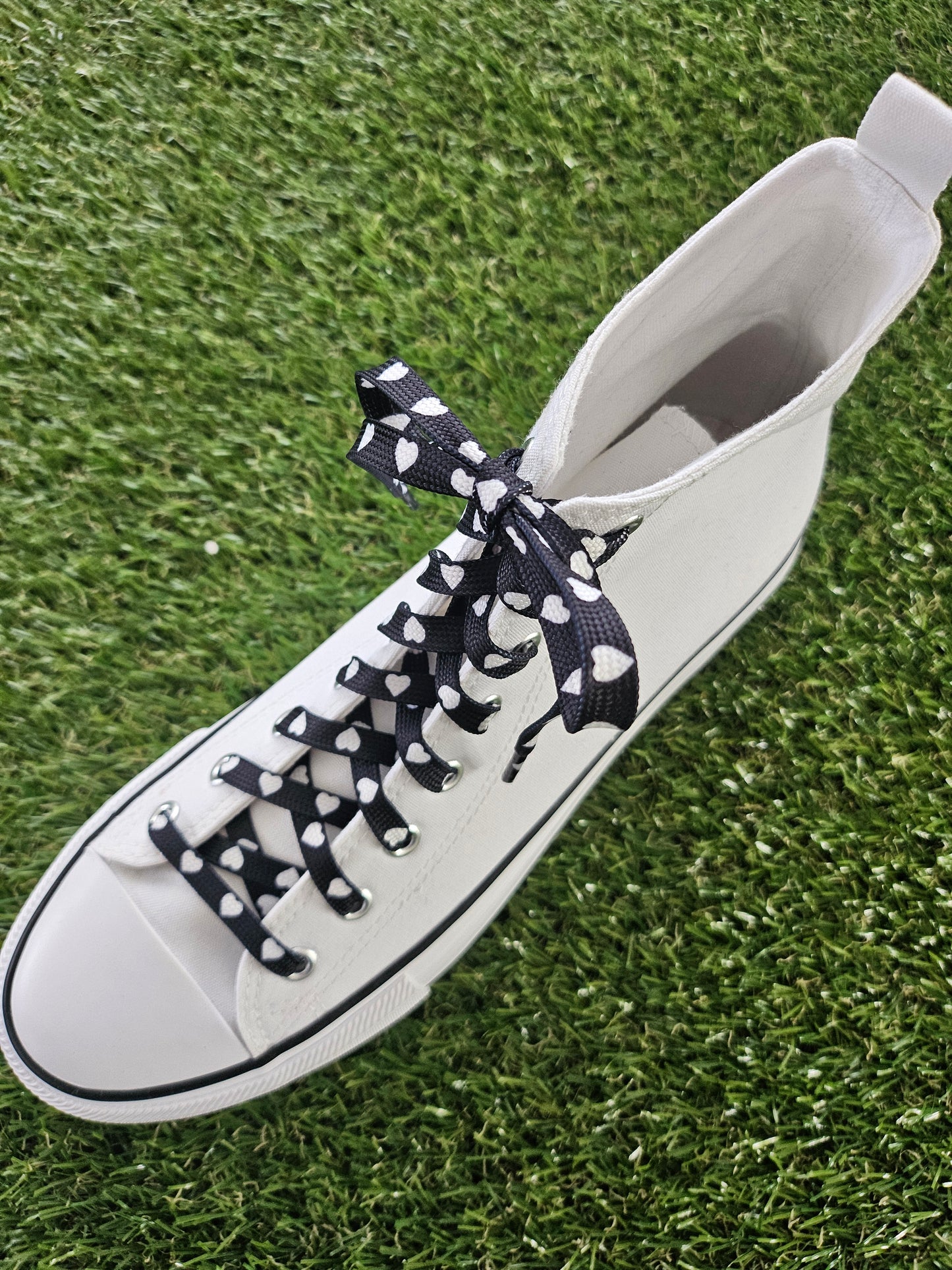 white canvas boot with black and white shoelaces on a grass background
