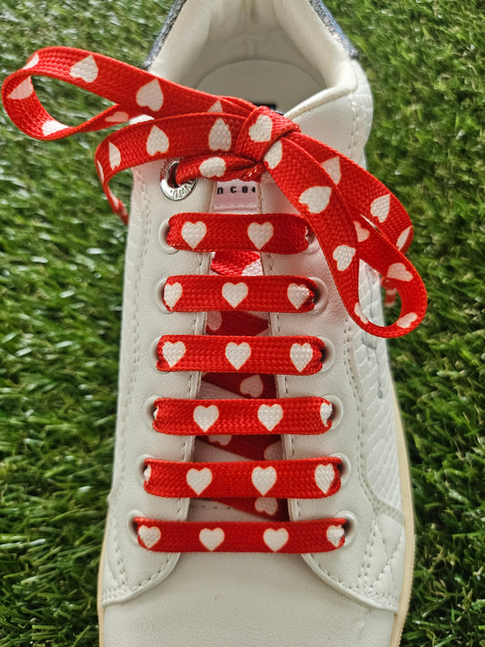 Red shoelaces with white heart pattern threaded through trainers